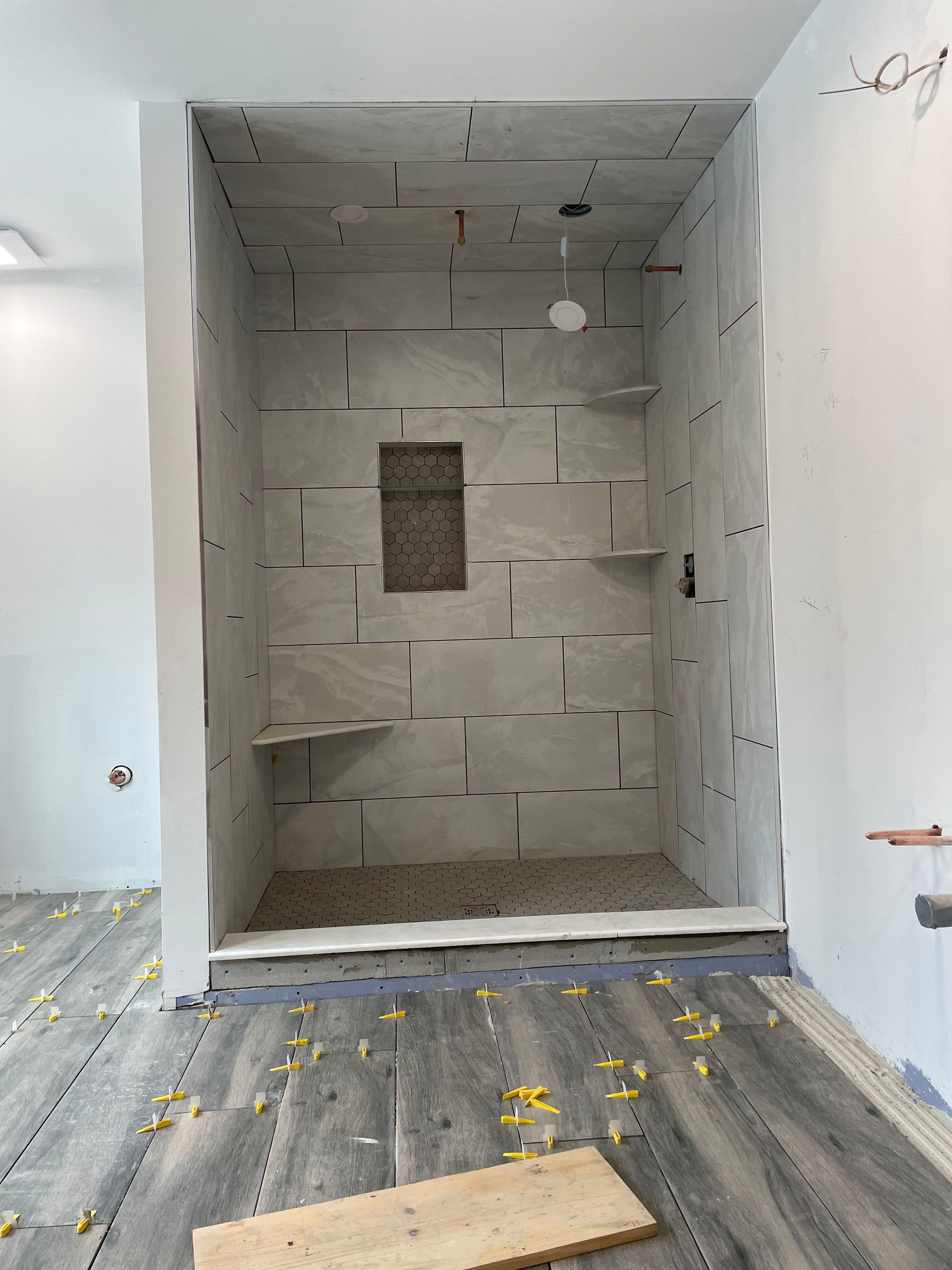 Partially finished room with a recessed tiled shower niche and gray wood-look flooring