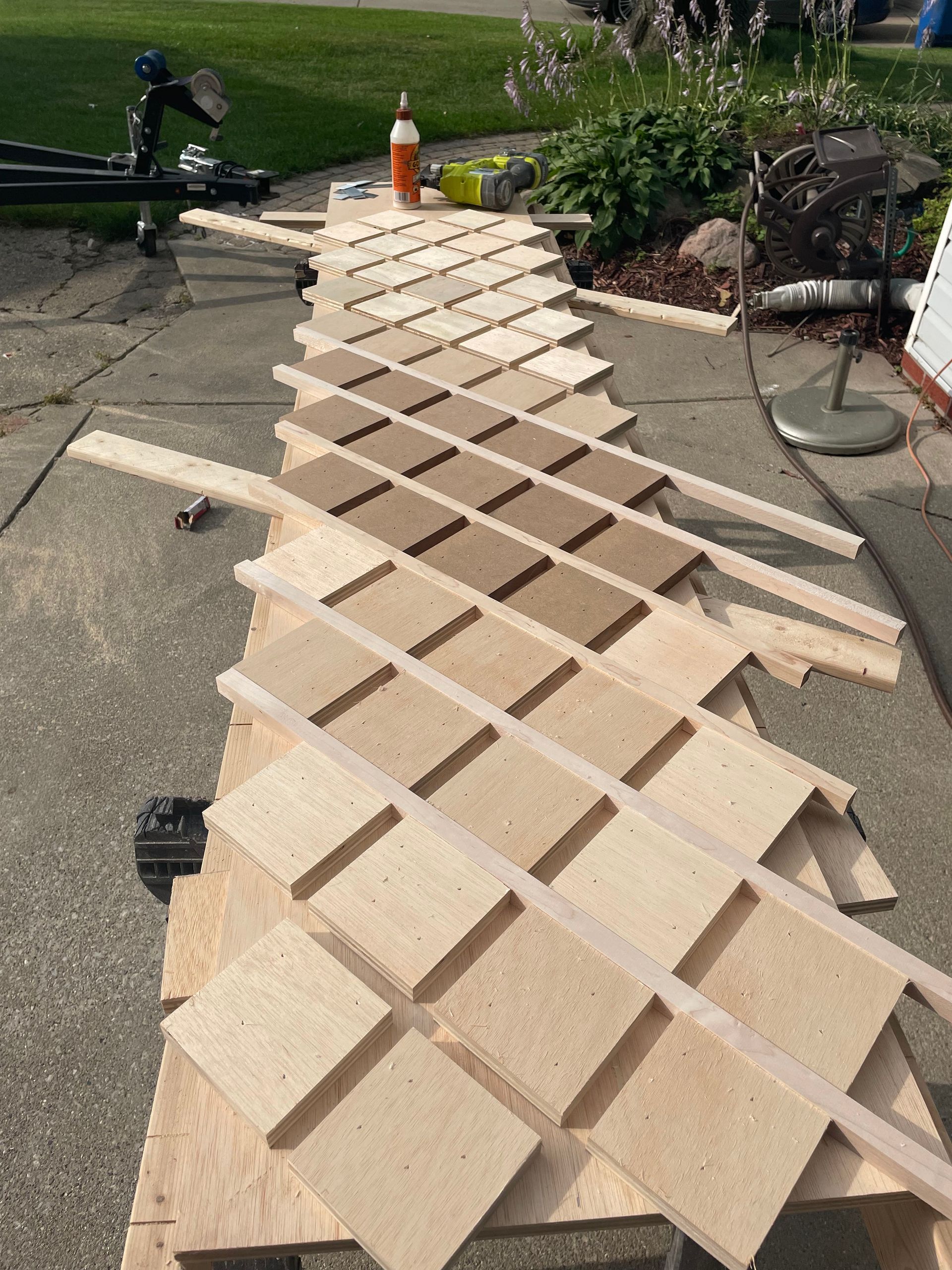 Wooden lattice panels laid out in a long row on a driveway for a construction or craft project