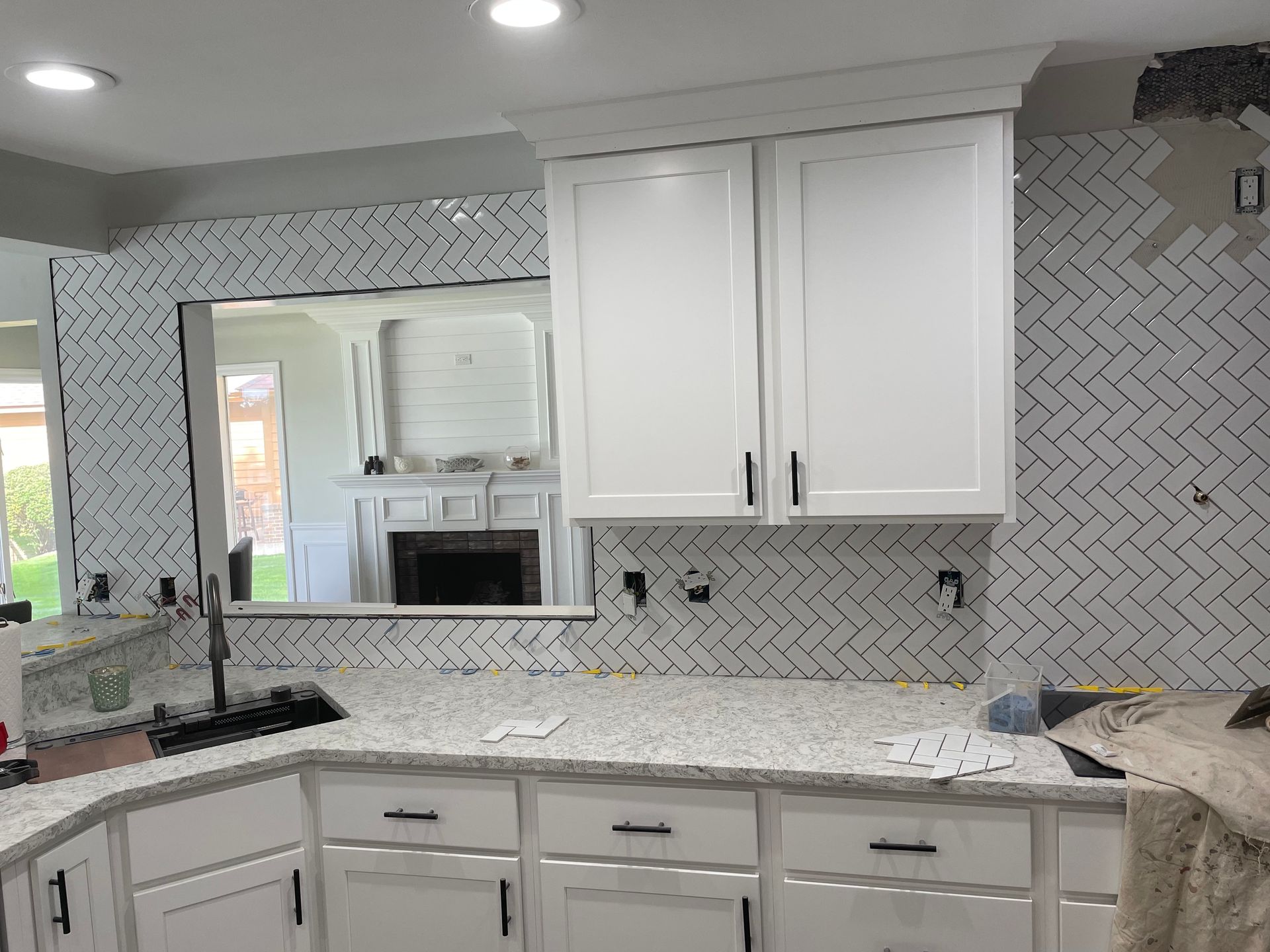 Modern kitchen with white cabinets, gray herringbone backsplash, and granite countertops