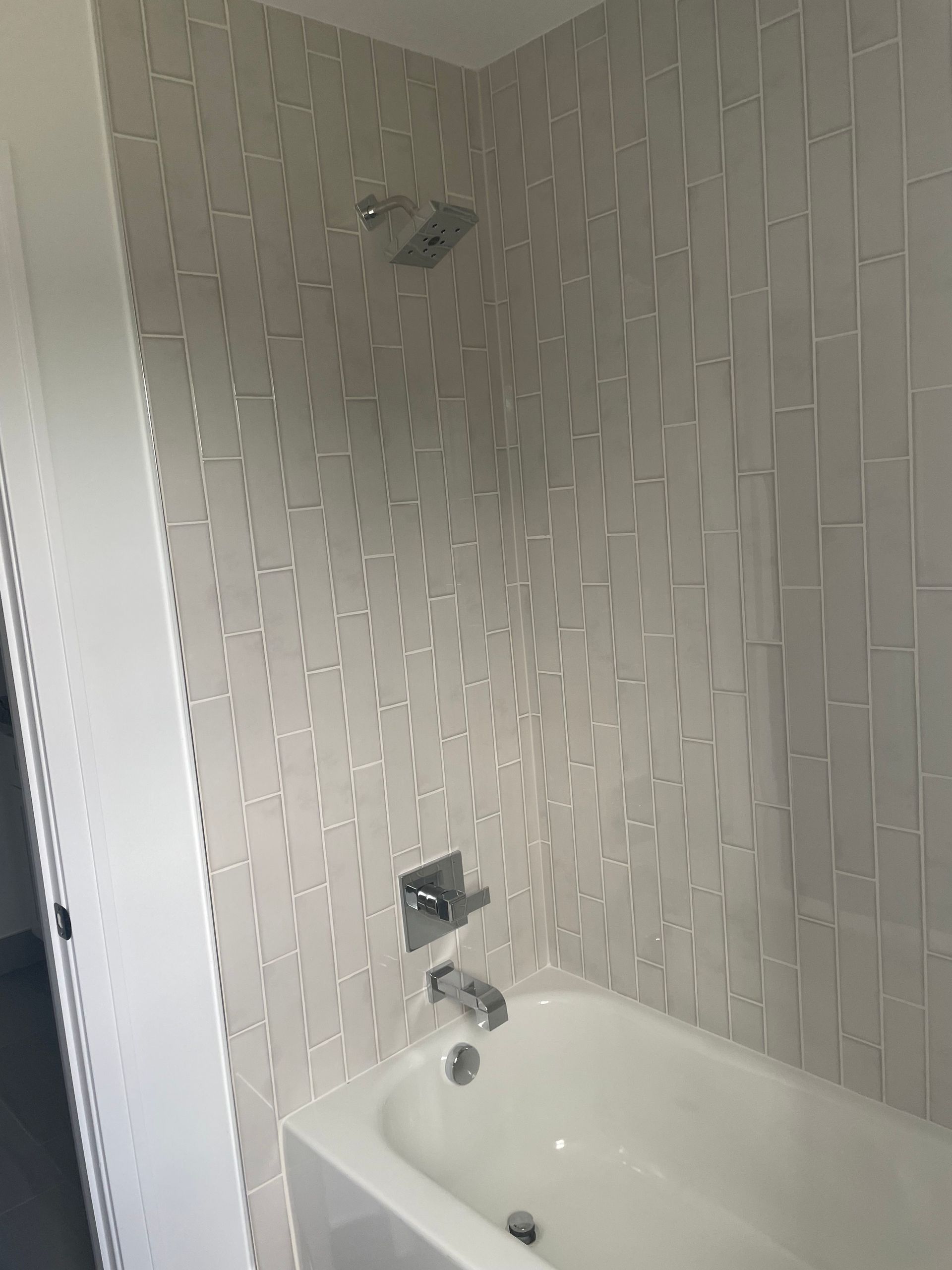 Small bathroom with white tile walls and a bathtub-shower faucet