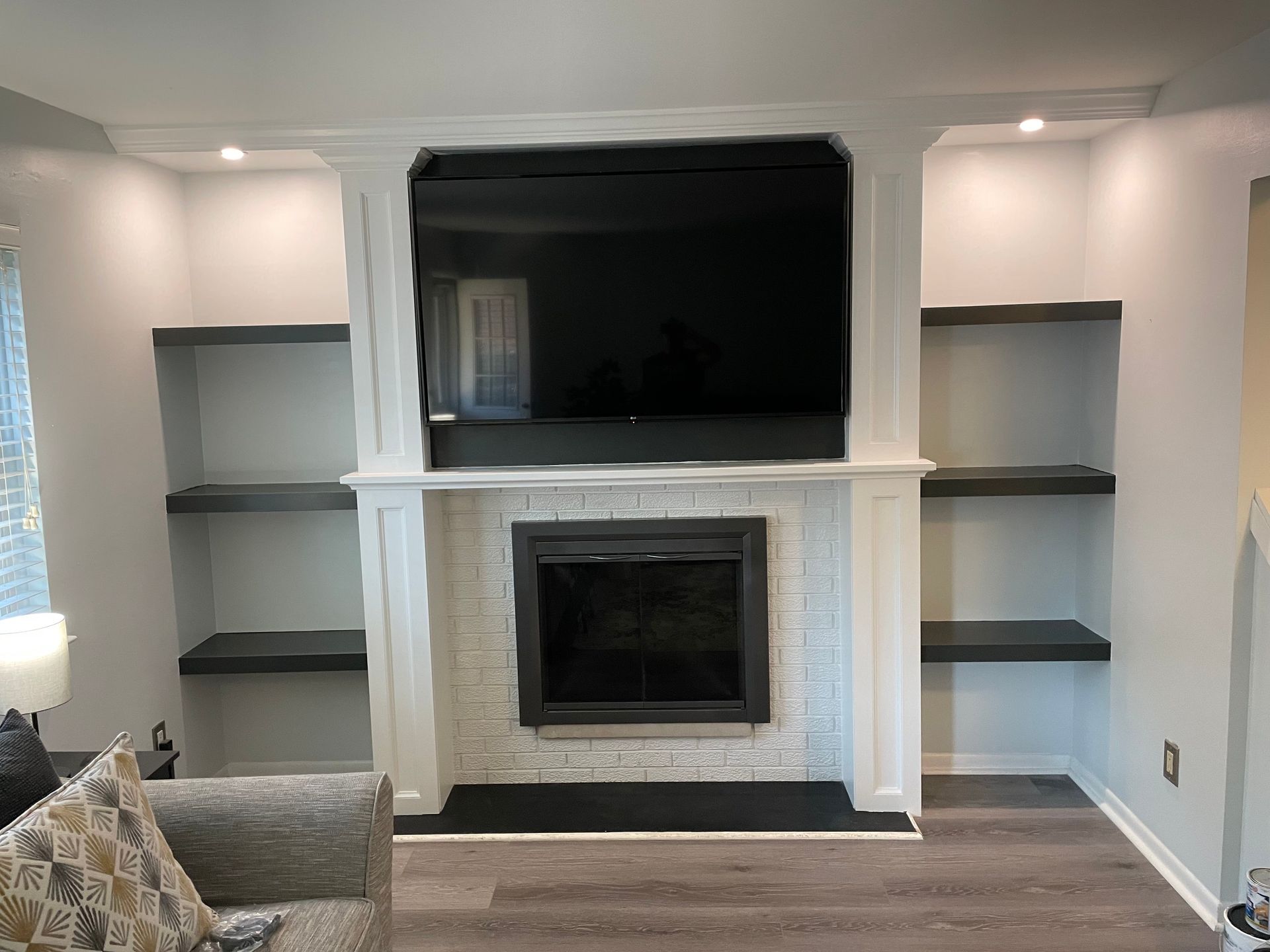 Living room with white built-ins, a central fireplace, and a large wall-mounted TV above it