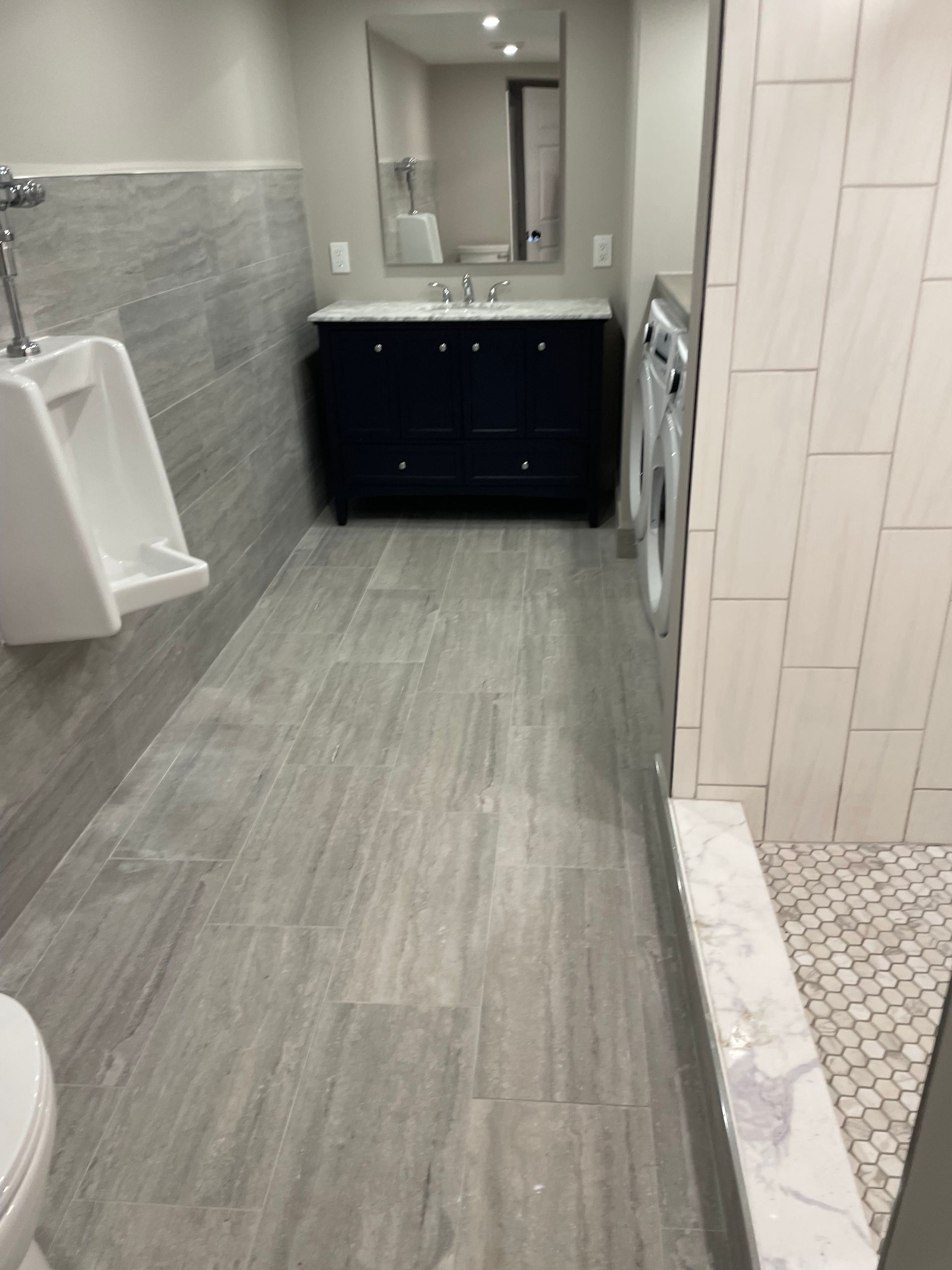 Bathroom with gray tile floor, black vanity, white sink, and a walk-in shower.