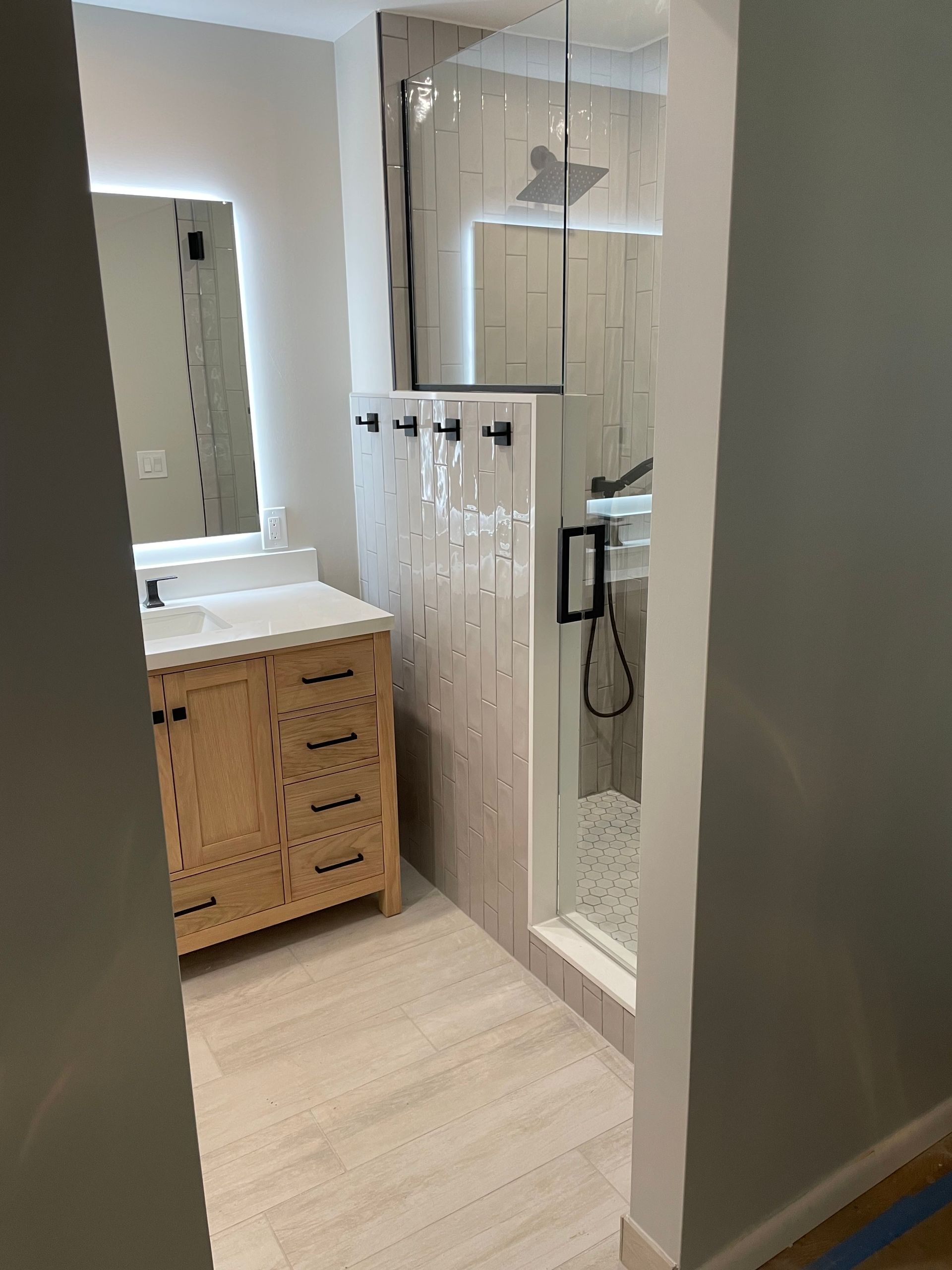 Bright bathroom with white shower, wicker vanity, and mirror under soft natural light