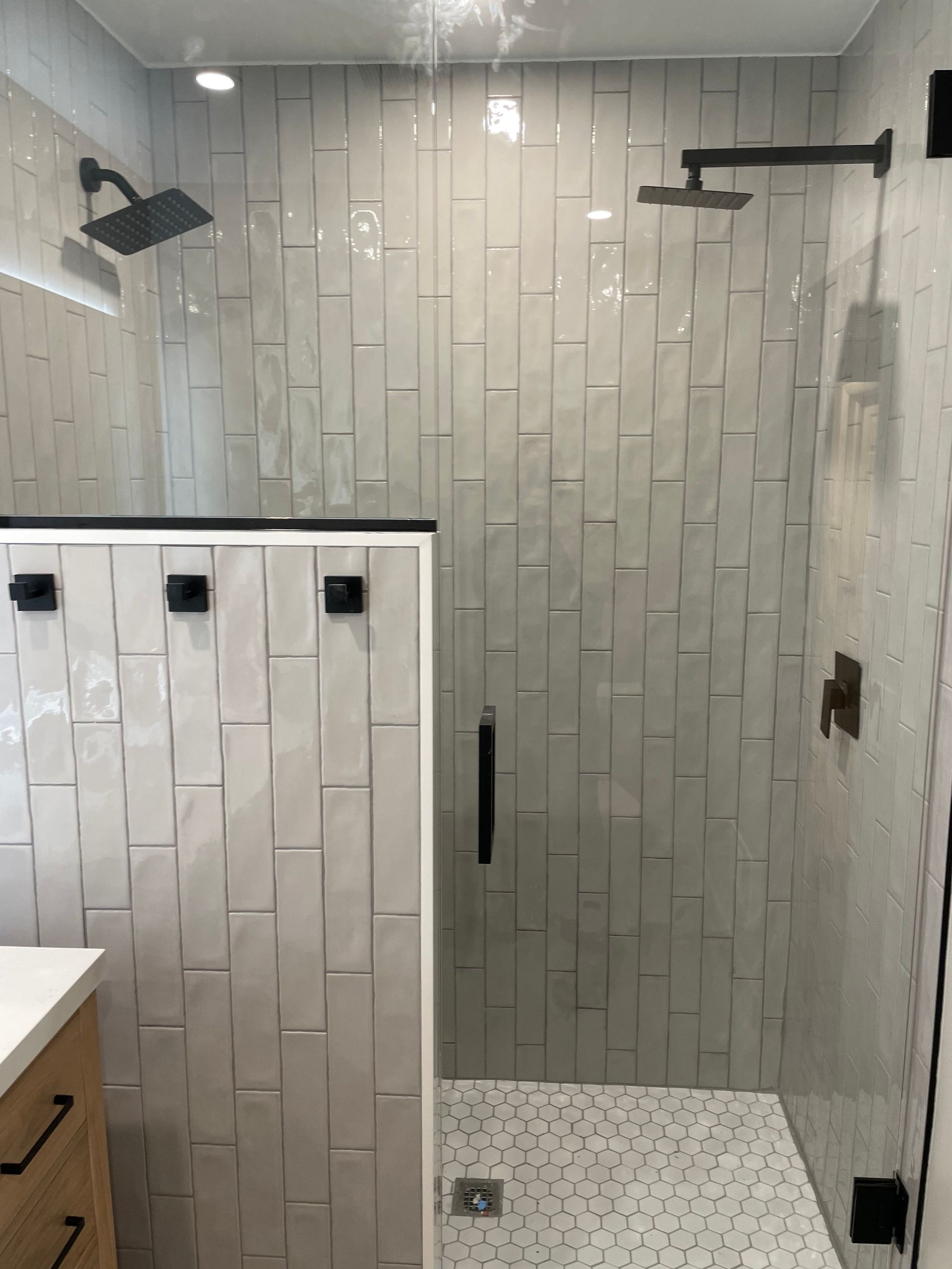 Modern tiled walk-in shower with black fixtures and glass door