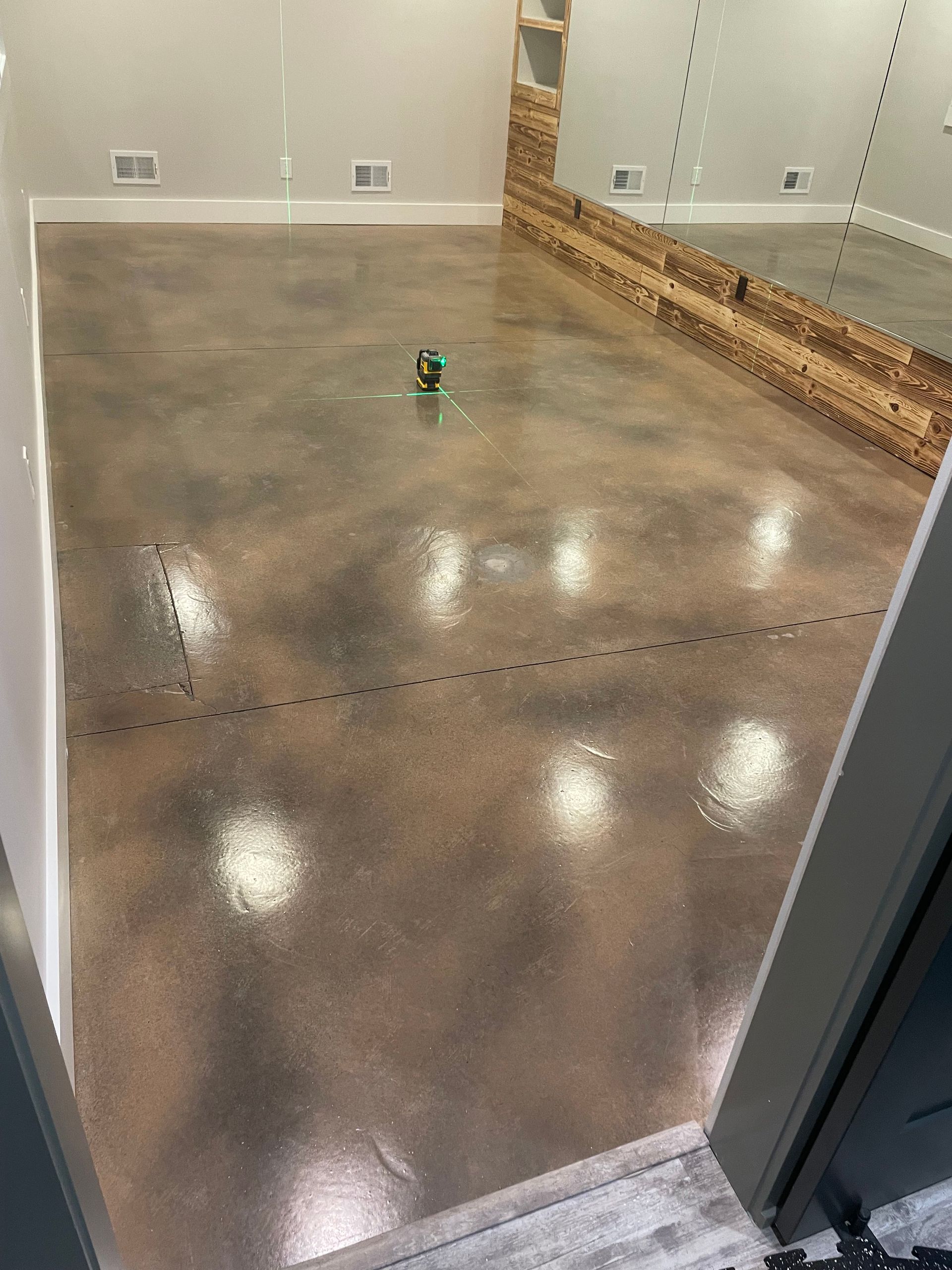 Polished concrete floor in an empty room, with a small green object near the center.