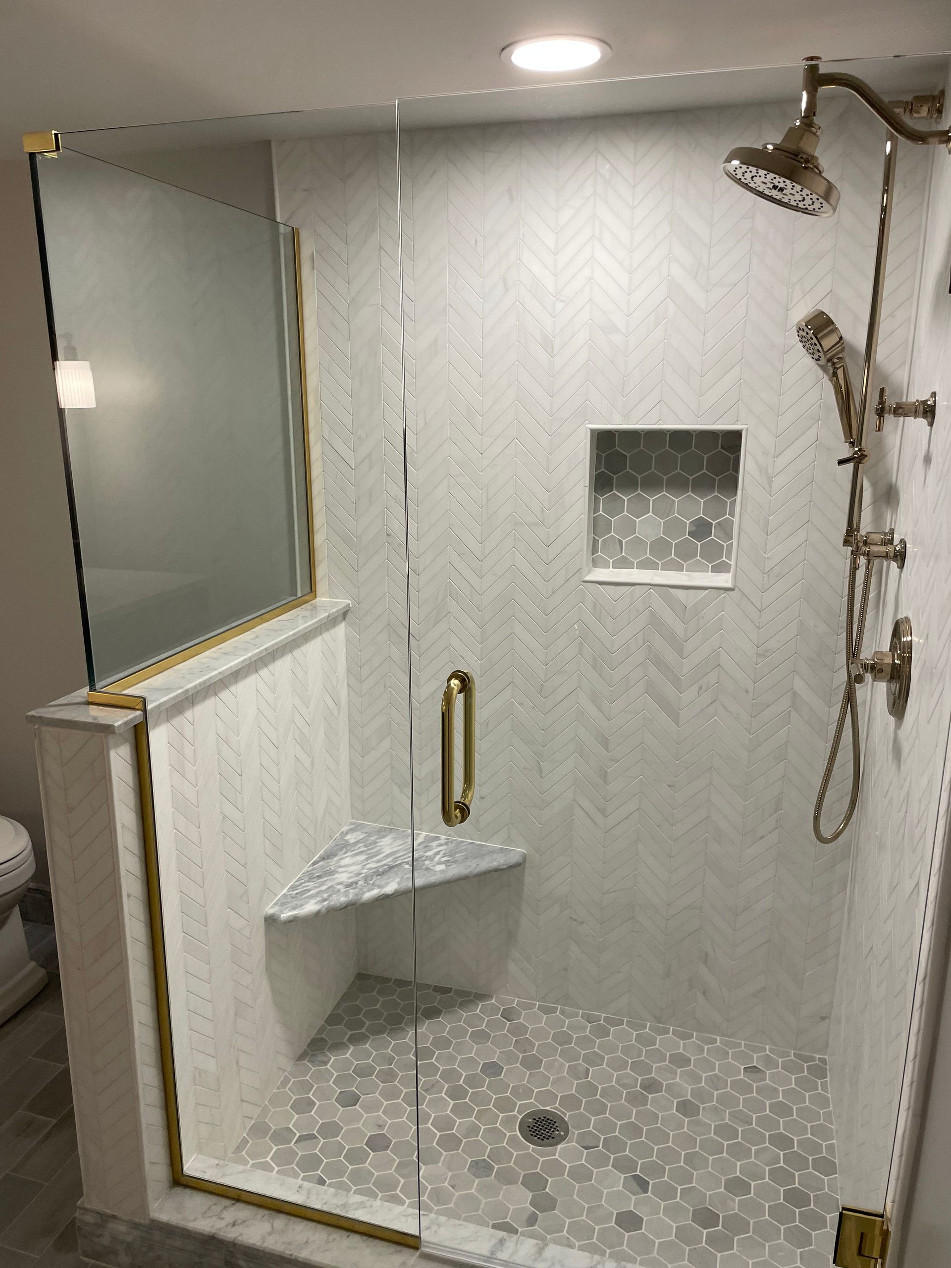 Accessible roll-in shower with grab bars, built-in bench, handheld shower, and tiled walls.