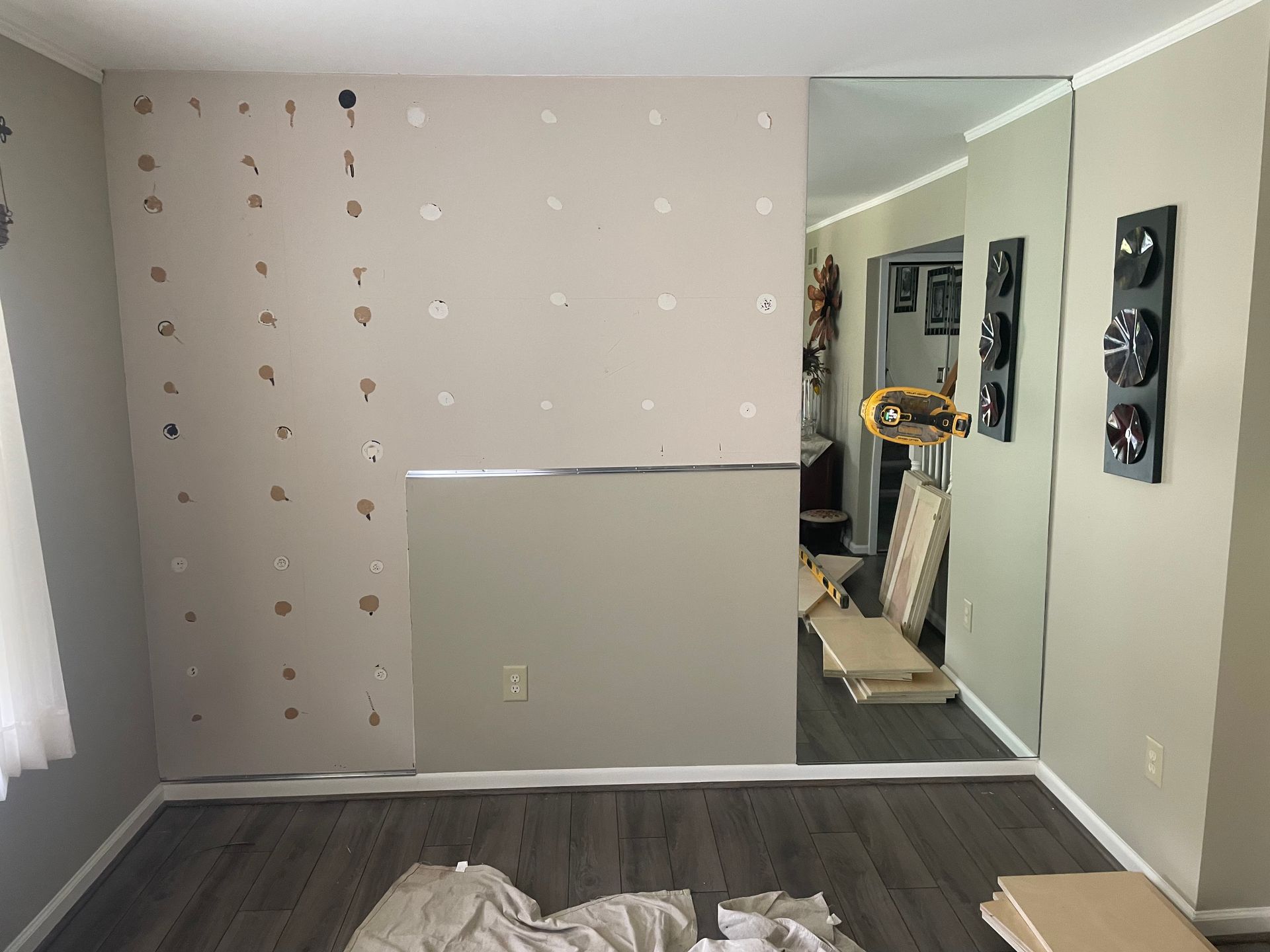 Empty room with beige walls, gray flooring, and a mirror beside a small exercise machine.