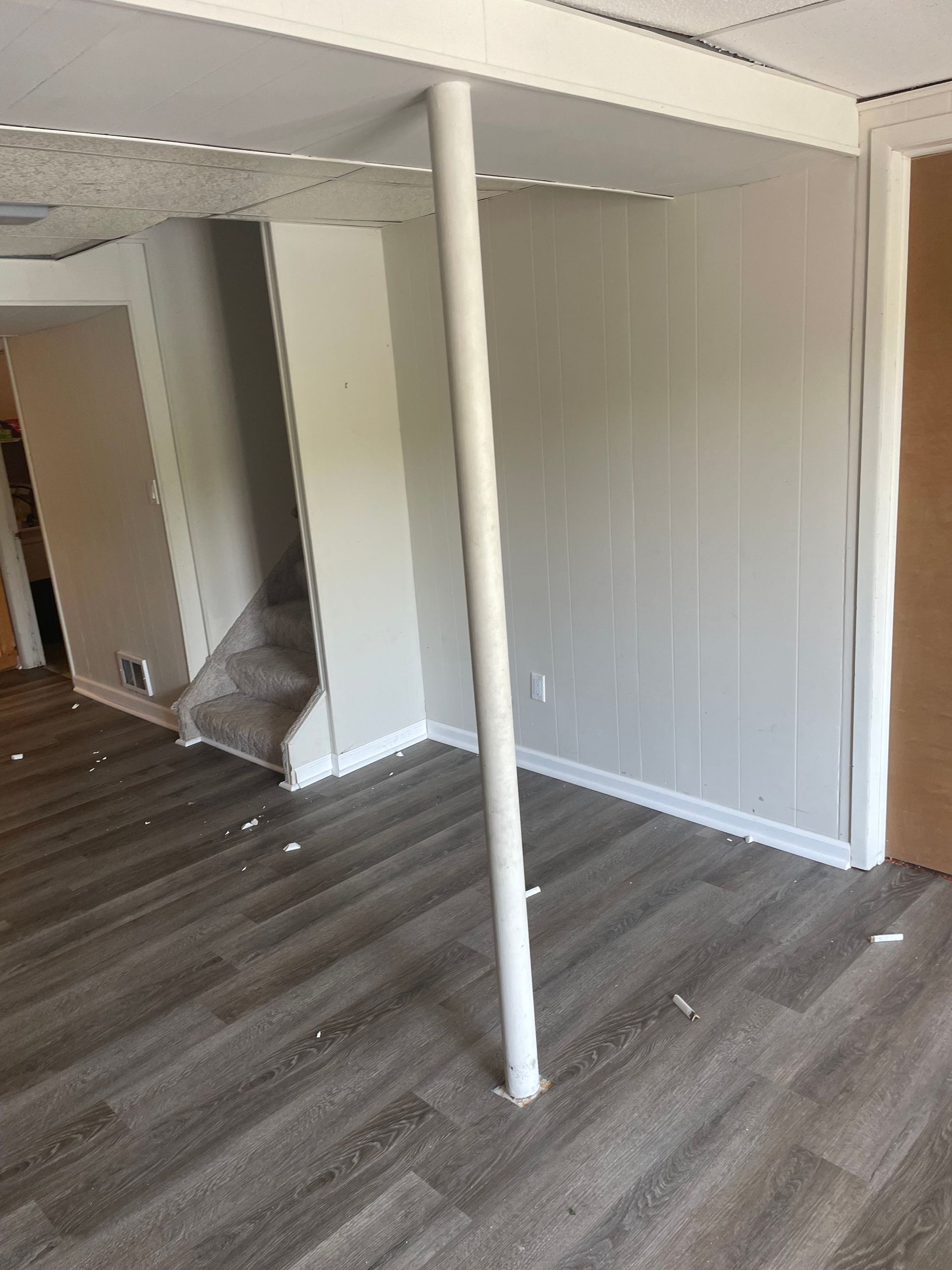 Empty room with gray wood floor, white walls, and a central support post.