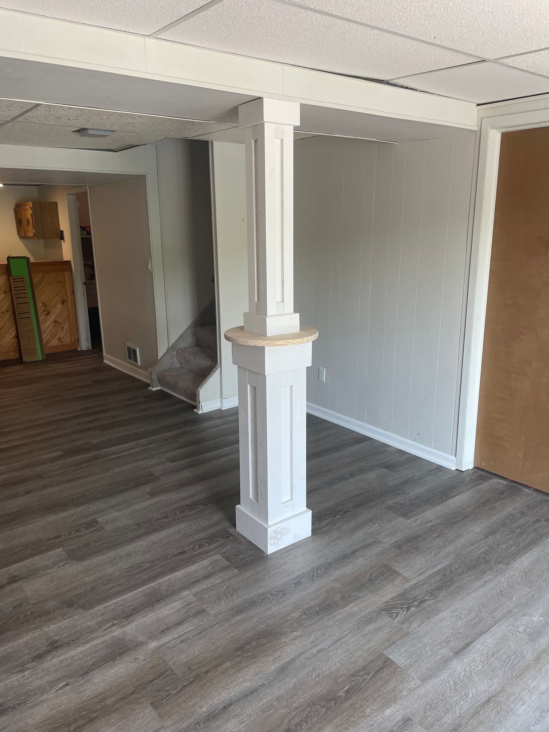 Empty room with gray wood floors, white walls, and a decorative central column.