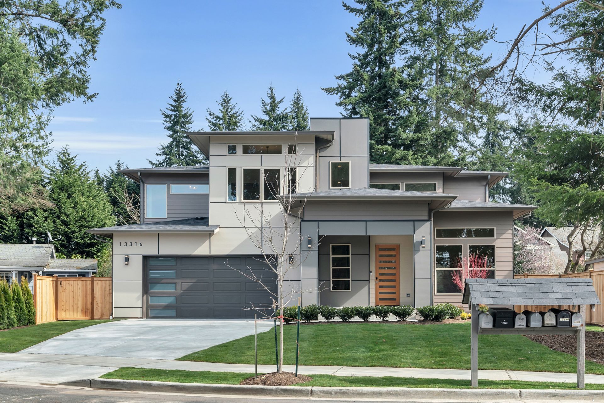 A modern house with a large driveway and a large garage surrounded by trees