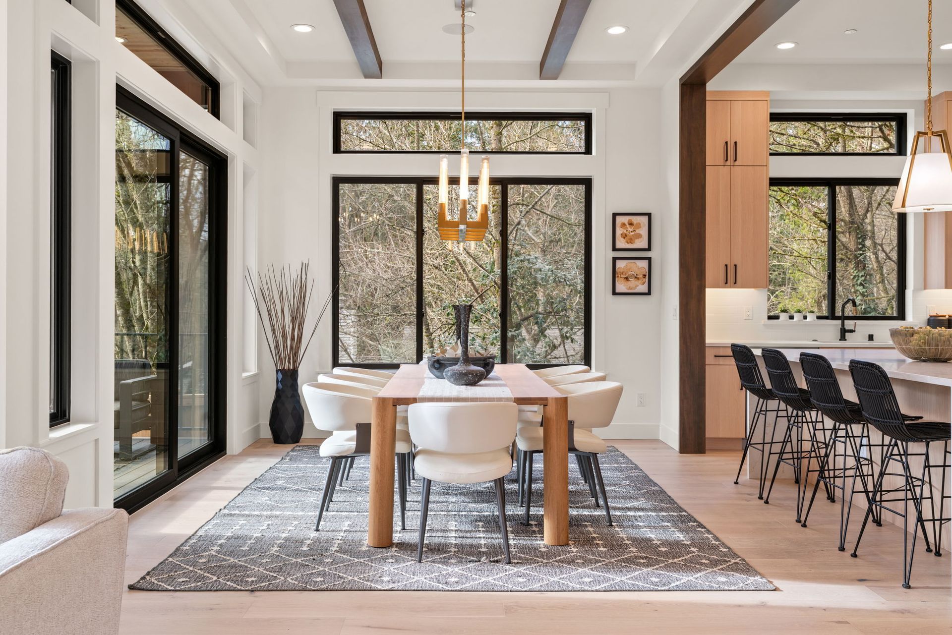 Dining room with modern decor, wooden table, white chairs, and large windows.
