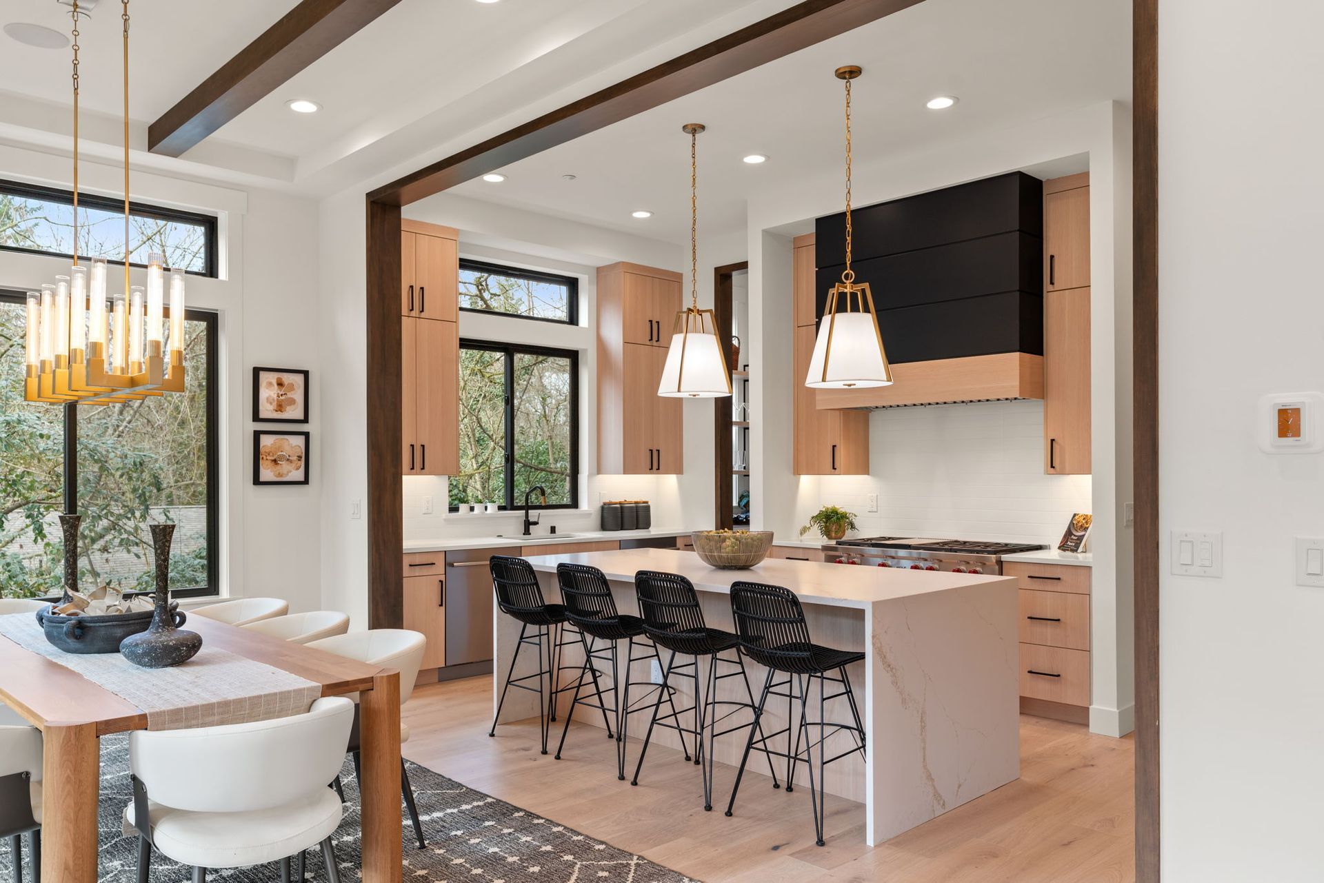 Modern kitchen with light wood cabinets, black accents, and a central island with black bar stools.