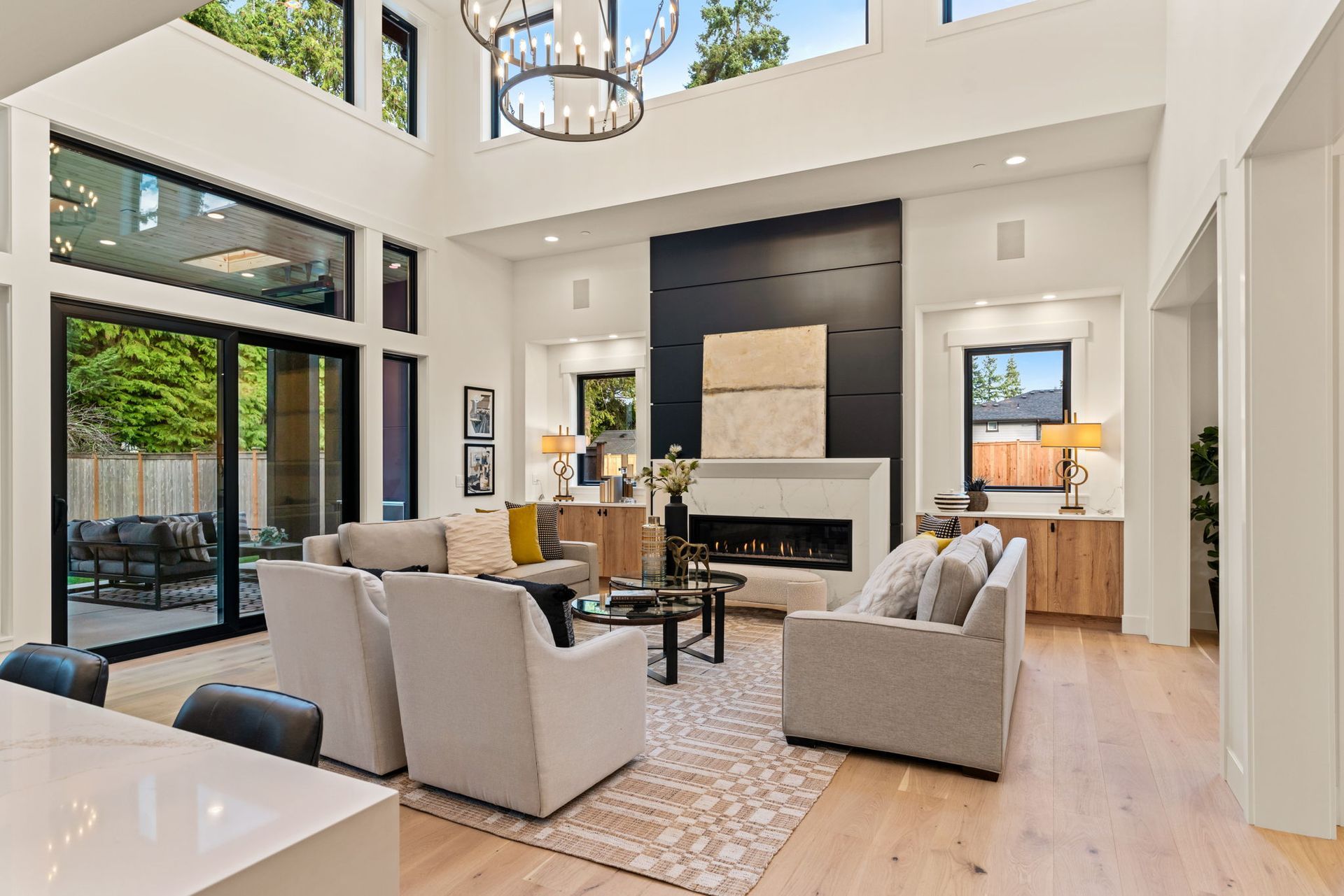 Modern living room with high ceilings, fireplace, and large windows looking outside.