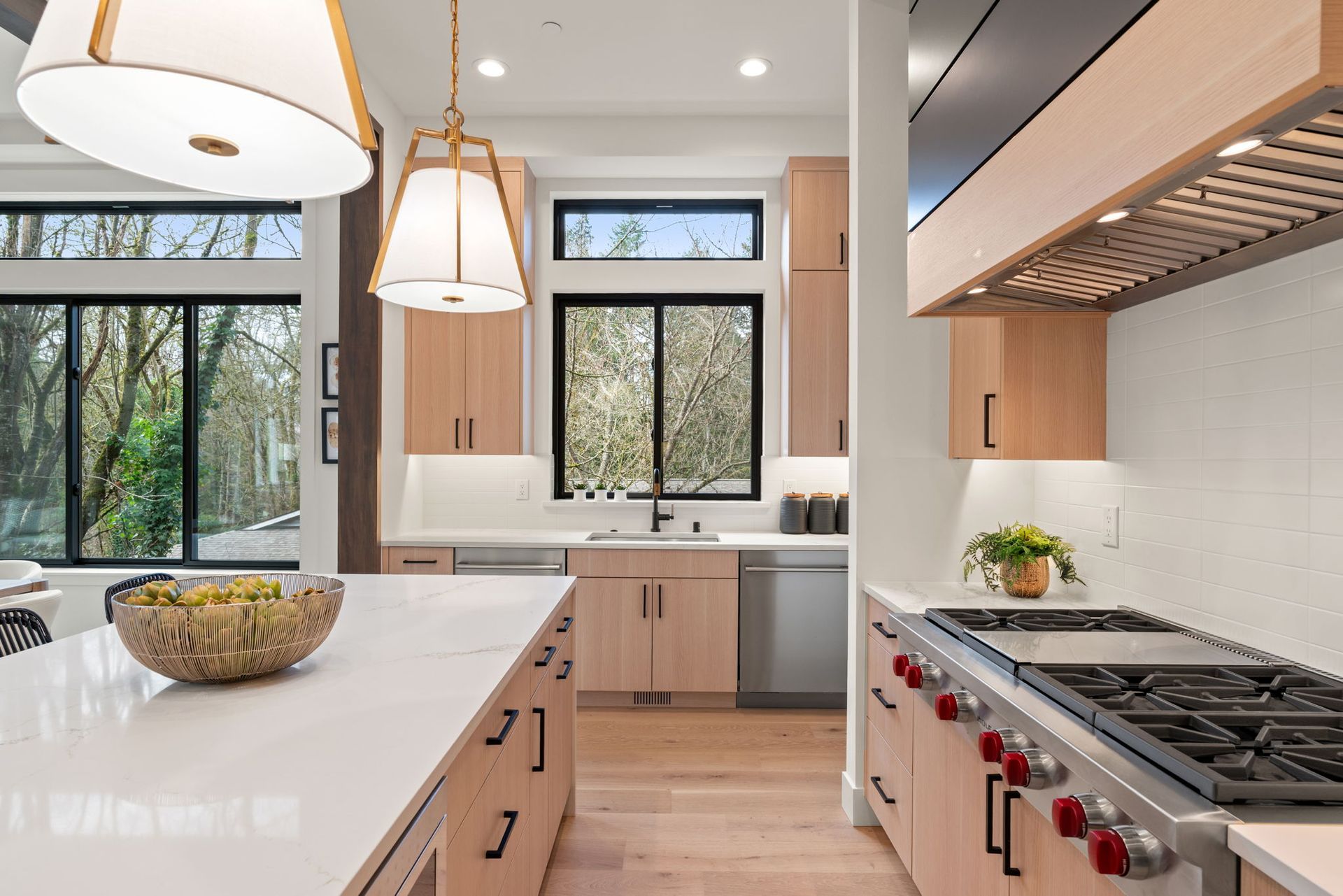 Modern kitchen with light wood cabinets, white countertops, and stainless steel appliances.