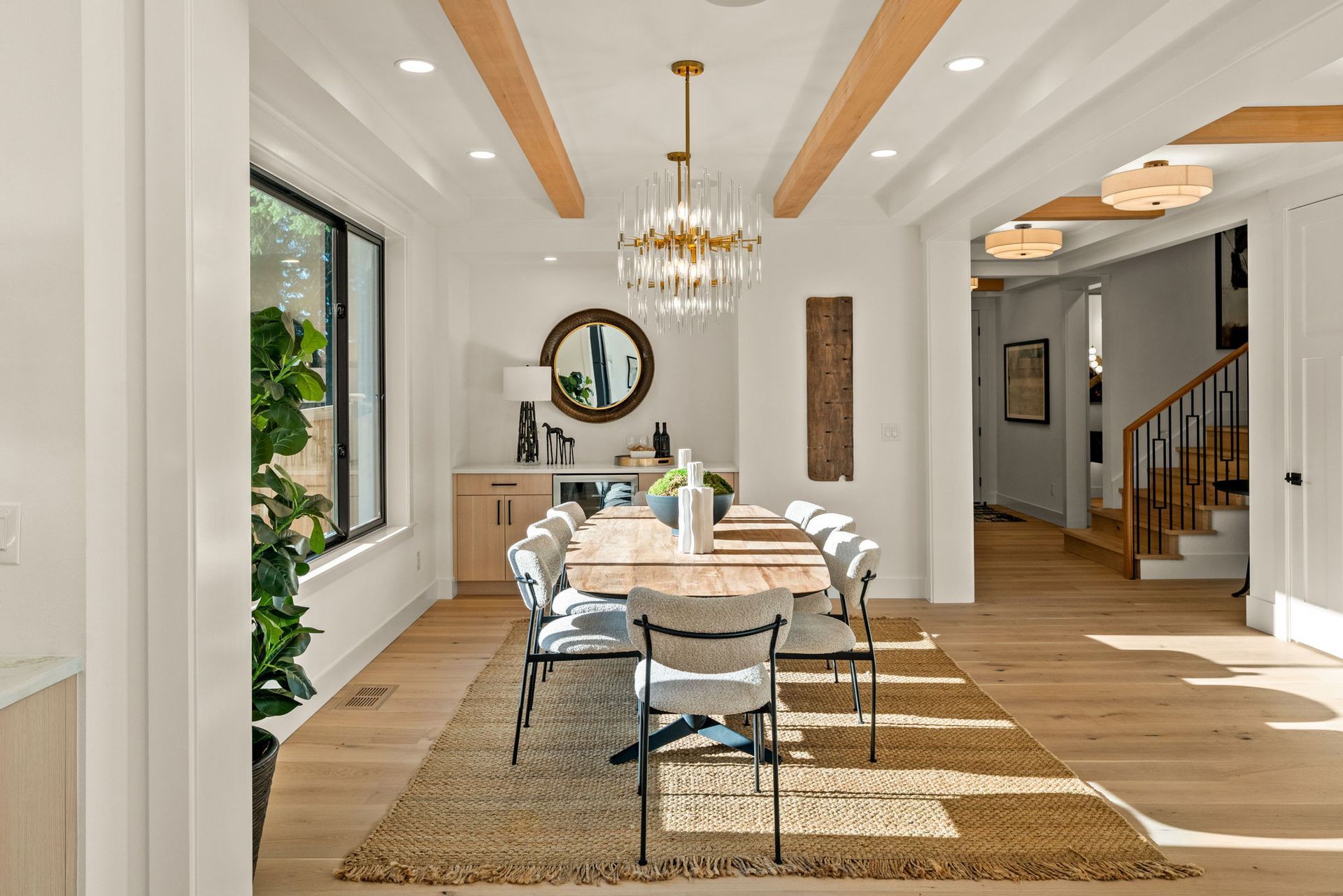 Dining room with wooden table, rug, chairs, chandelier, and a view of stairs.