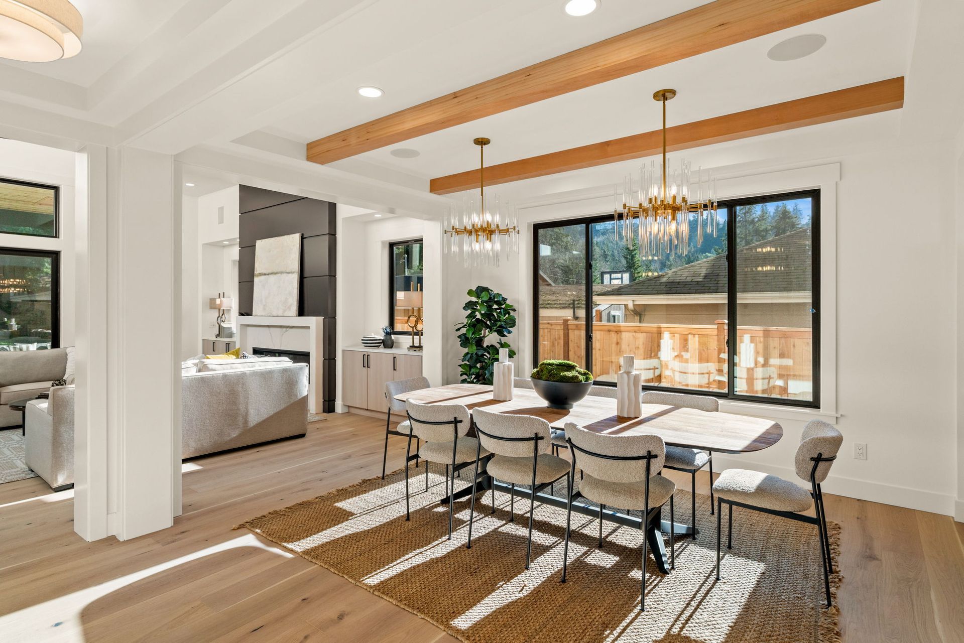 Dining room with table, chairs, chandeliers, windows, and light wood floors.