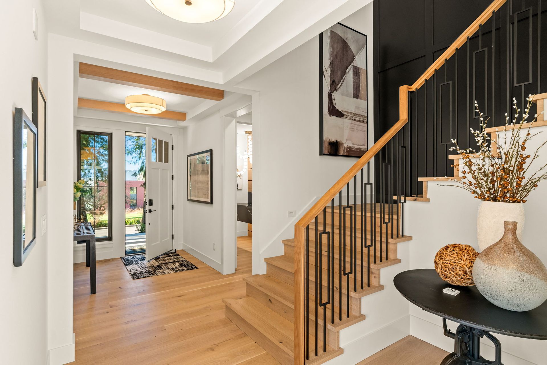 Entryway with staircase and decor. Wooden stairs, black railing, and white walls.