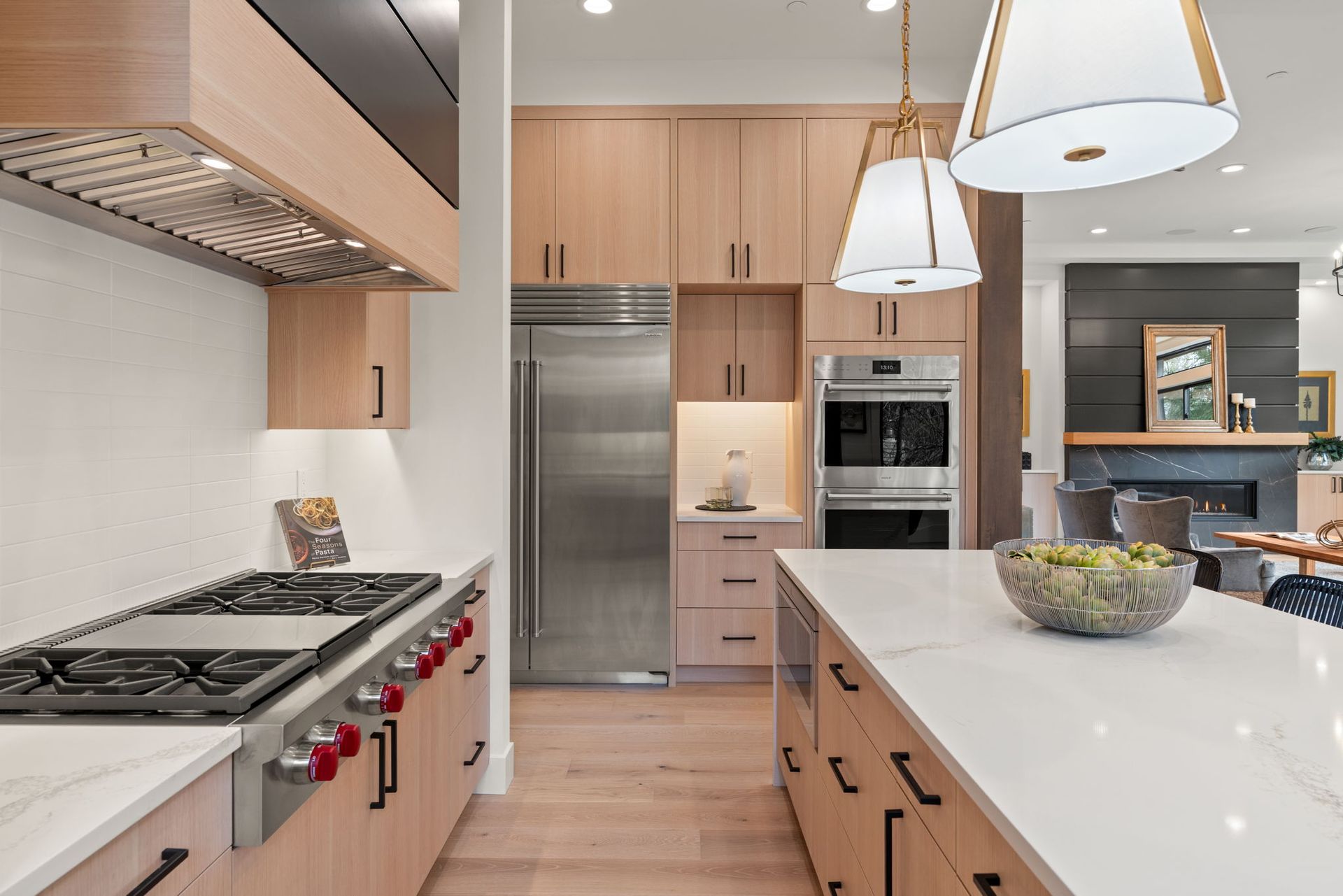 Modern kitchen with light wood cabinets, stainless steel appliances, and white countertops.
