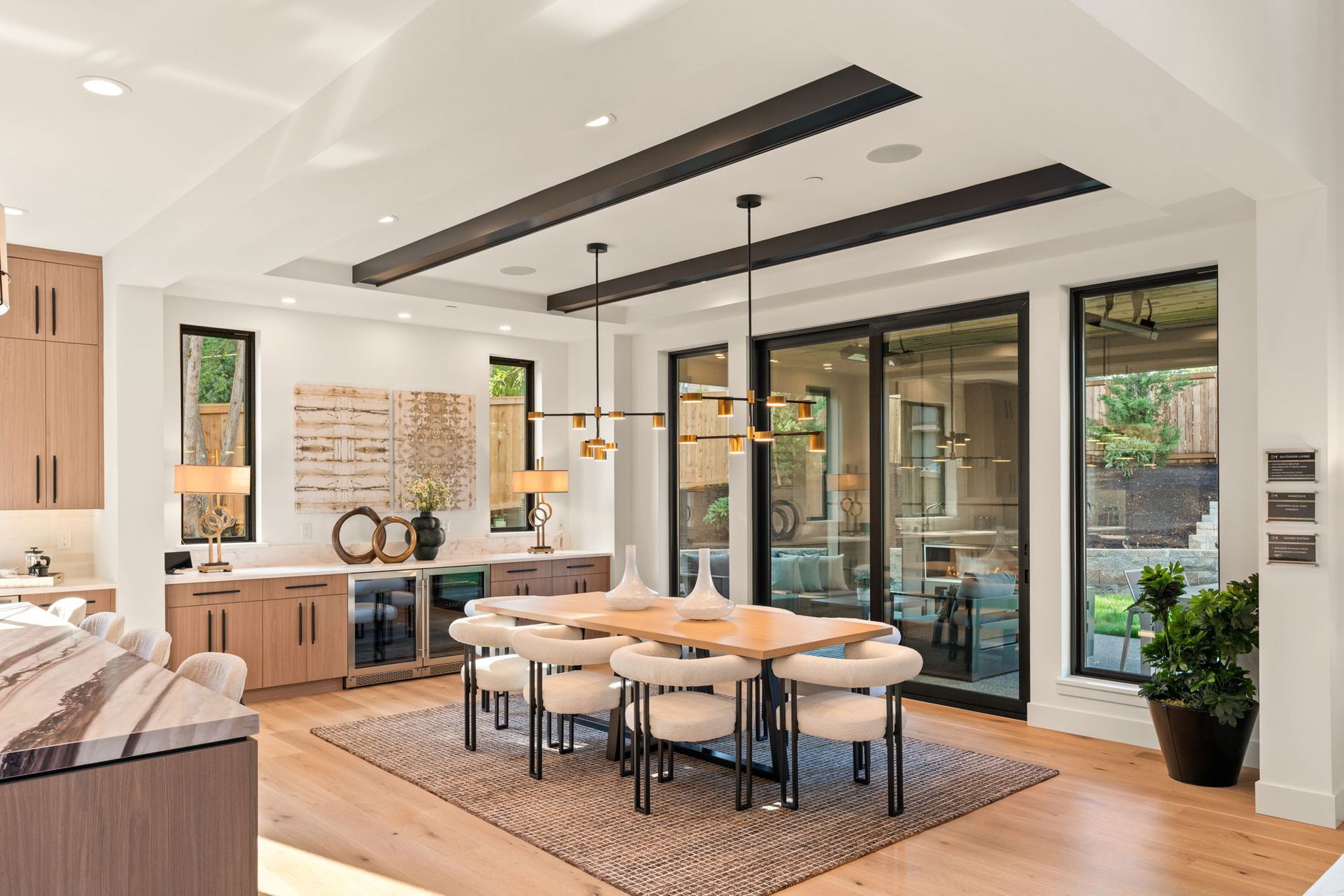 Bright modern dining room with round table, black chairs, and large glass sliding doors to a patio