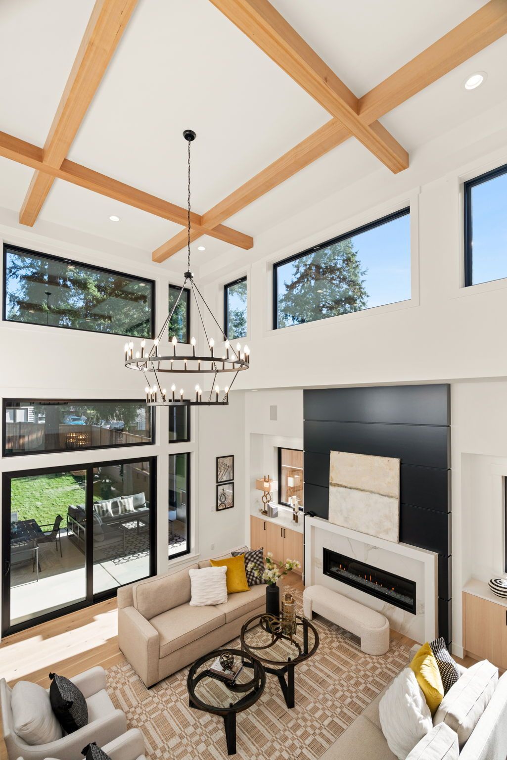 High-ceilinged living room with light wood beams, large windows, and modern furniture.