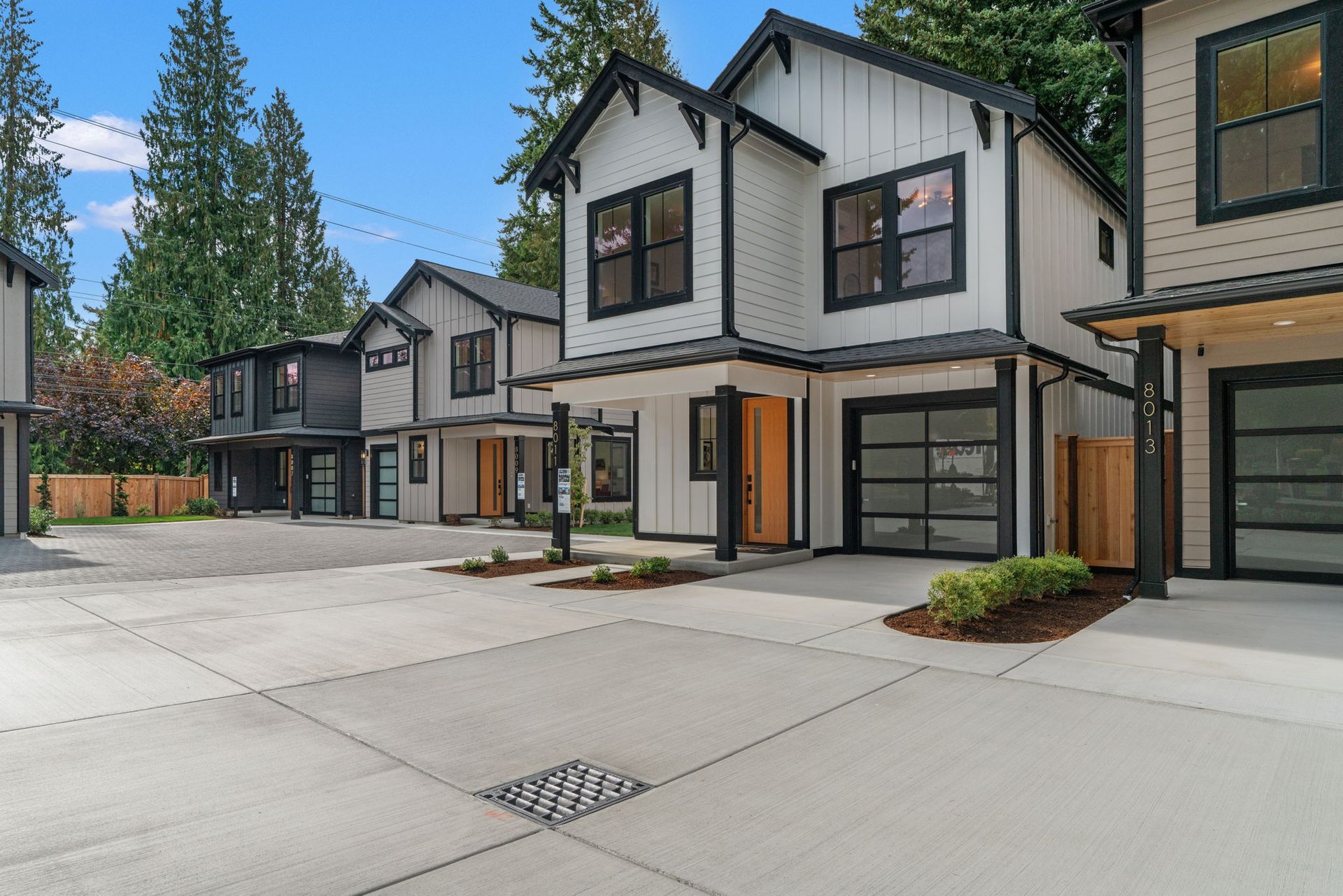 Two-story modern home with white siding, black trim, and glass garage door.