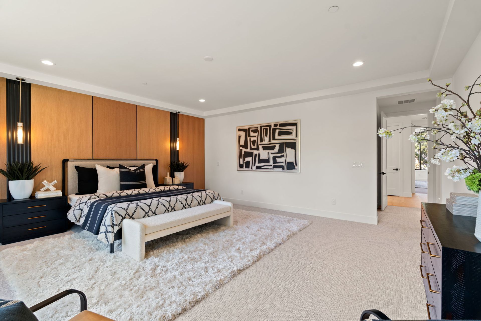 Modern bedroom with wood accent wall, upholstered bed, large rug, and minimalist decor