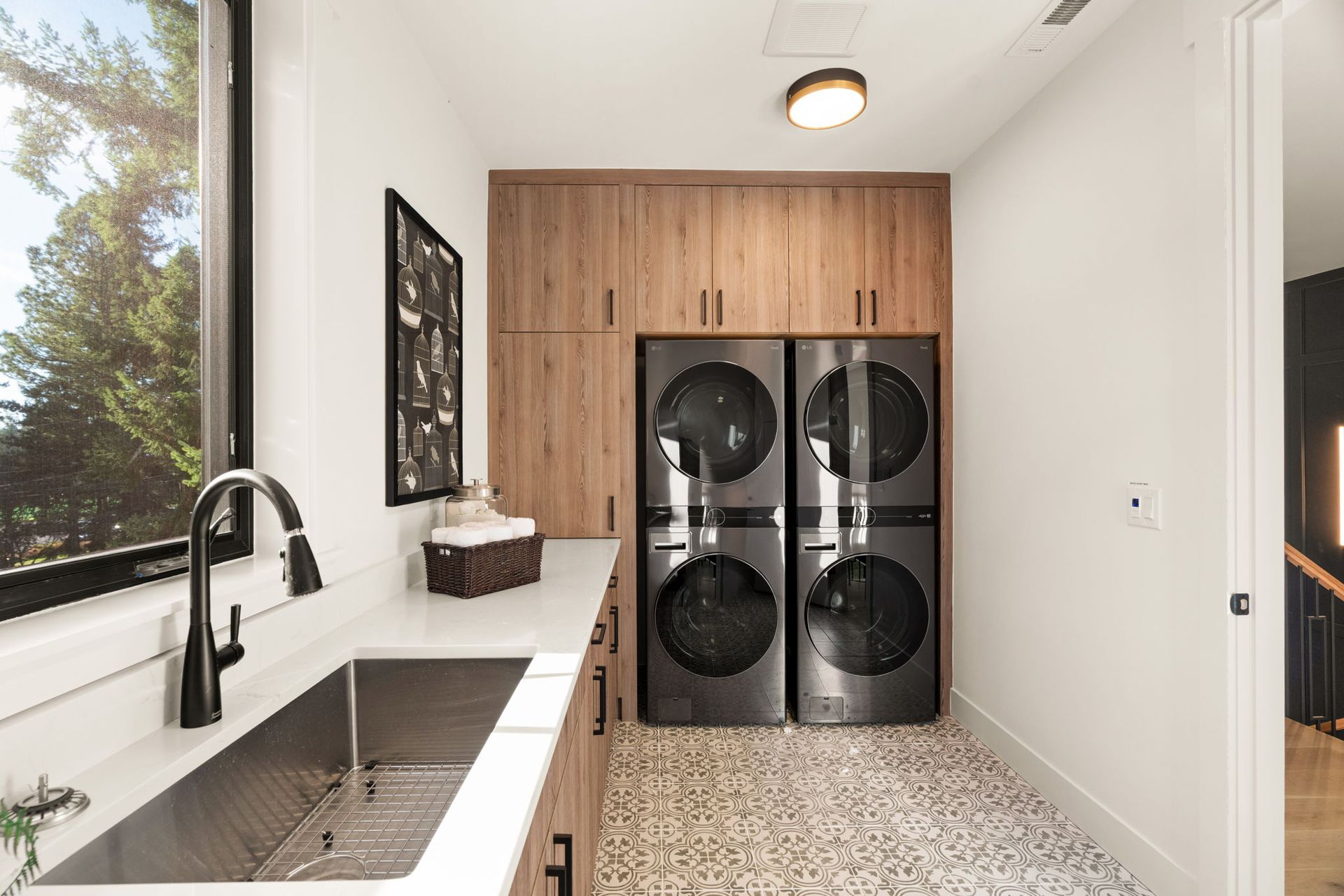 Laundry room with stainless steel sink, stacked washer/dryer, and wood cabinetry.