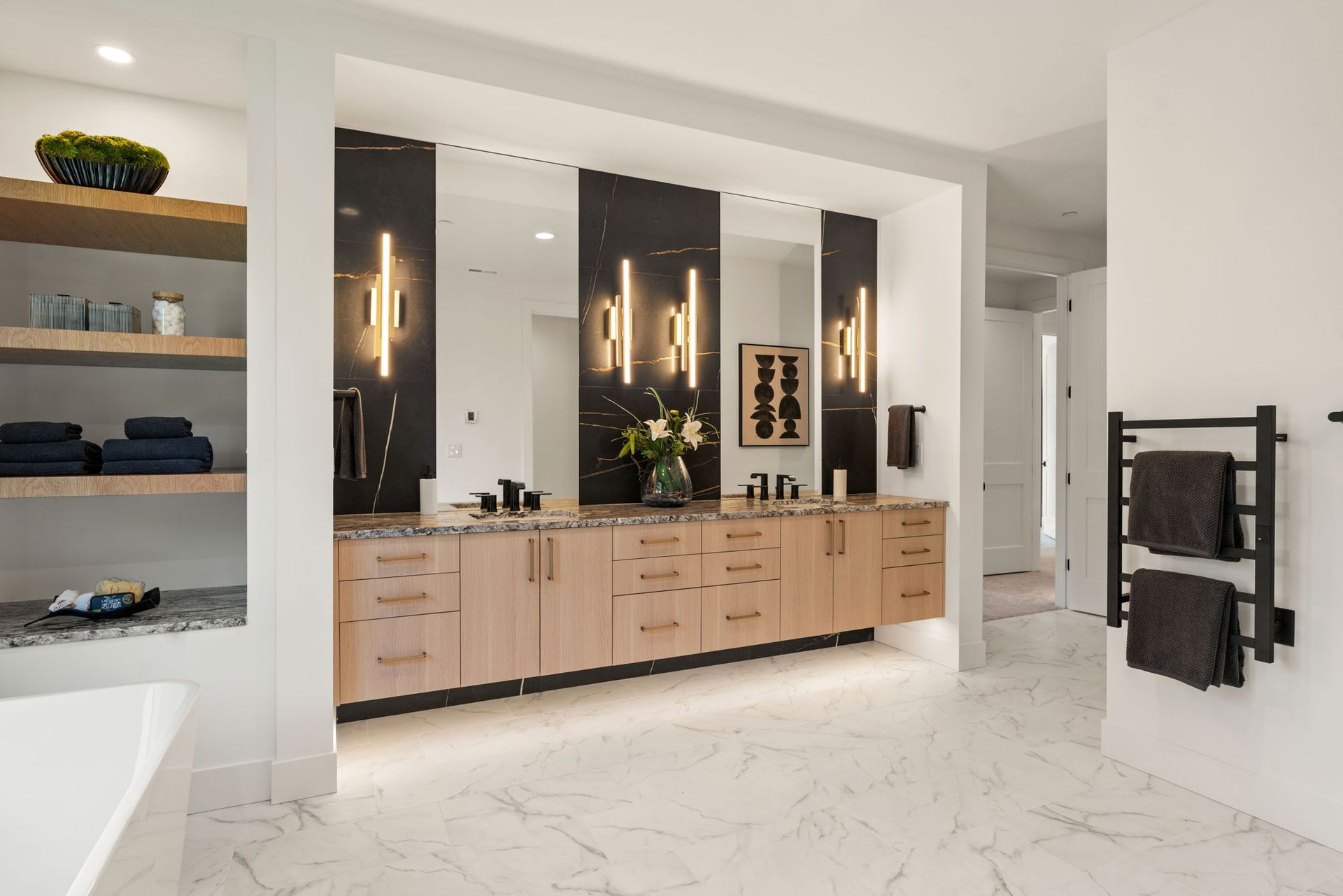 Modern bathroom with double vanity, wood cabinets, large mirrors, and white marble floors