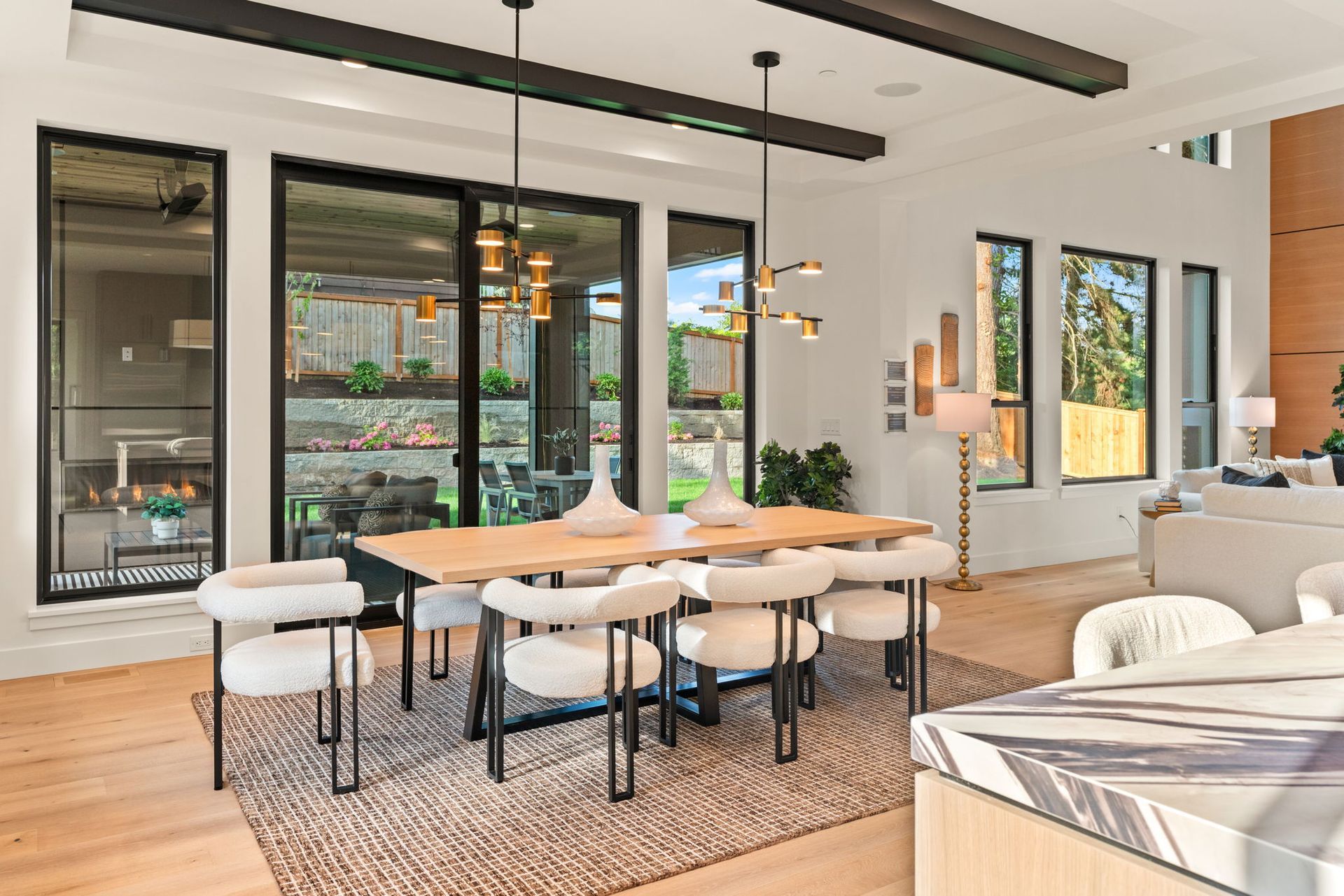 Modern open-plan dining and living room with glass doors, woven chairs, and a round wood table