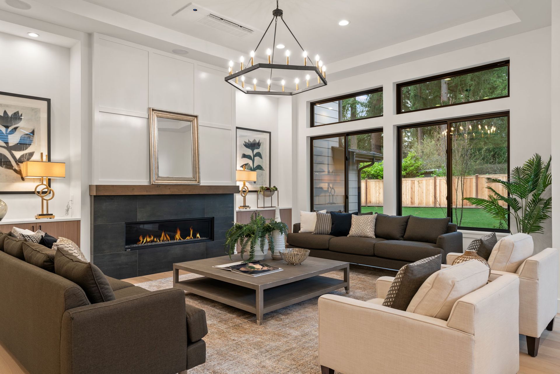 Spacious living room with fireplace, large windows, modern furniture, and chandelier.