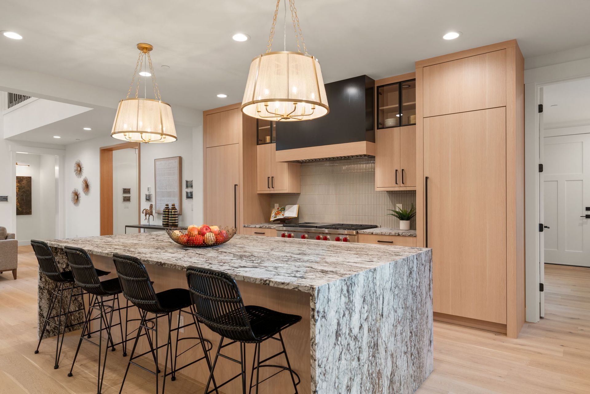 Modern laundry room with wood cabinets, white counters, black washer-dryers, and a window.