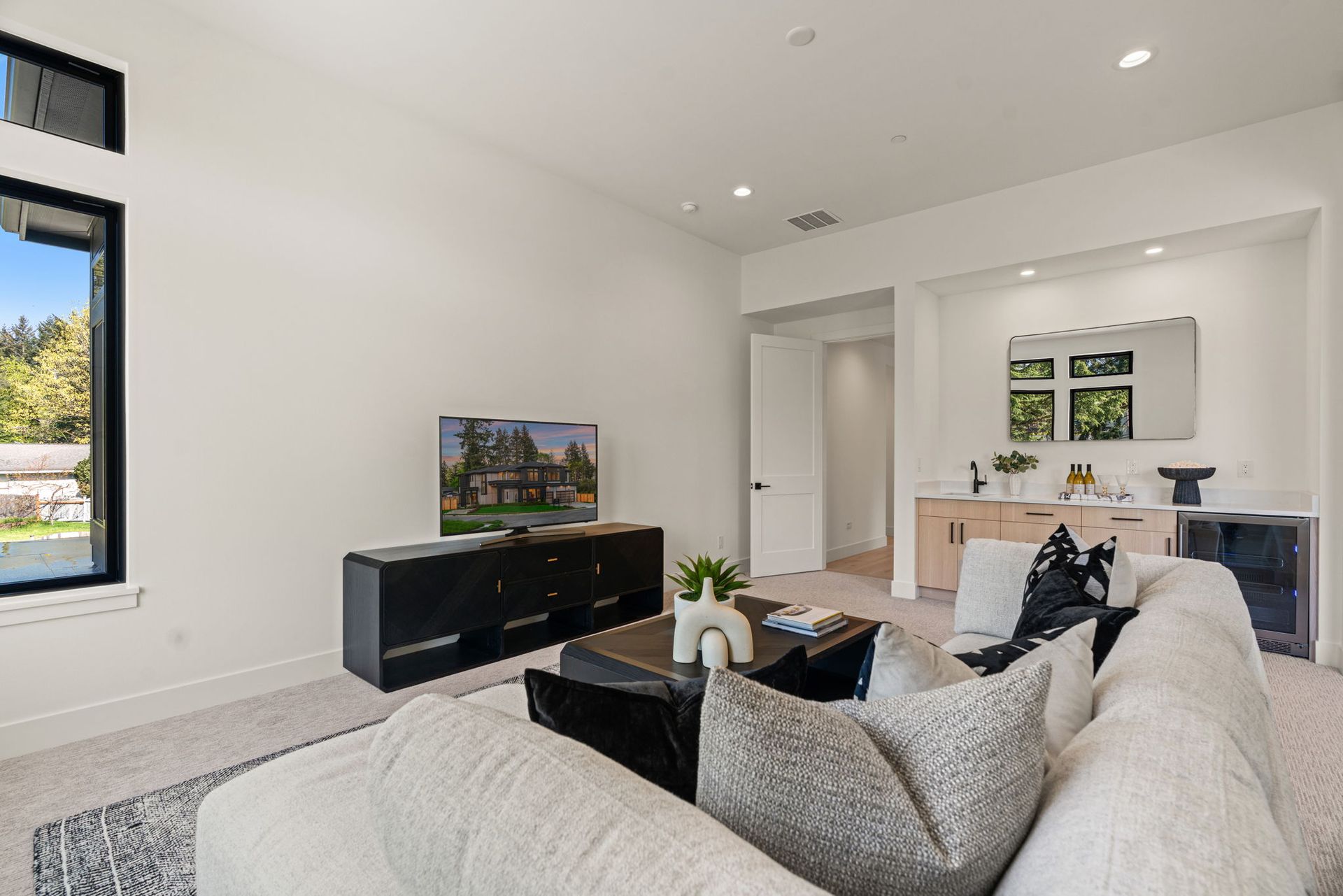 Bright modern living room with sectional sofa, TV console, and open view into dining area