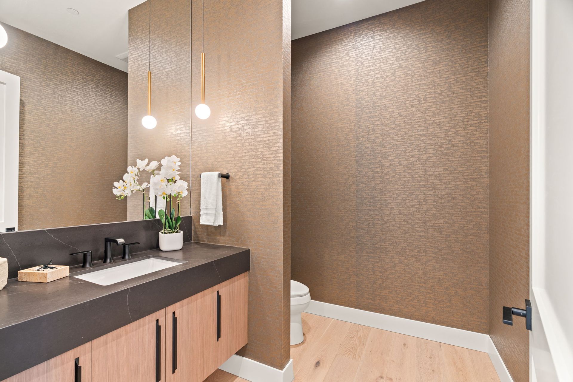 Modern bathroom vanity, wood cabinets, pendant lights, and textured beige walls
