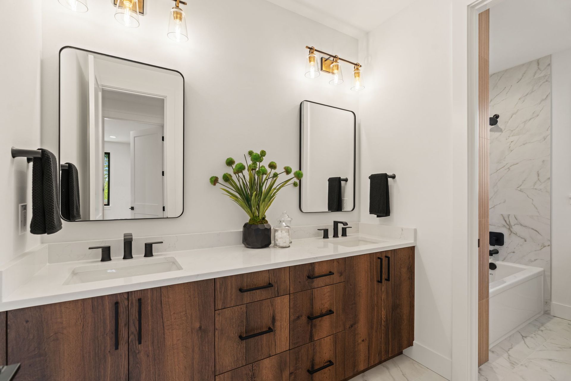 Modern bathroom vanity with double sinks, mirrors, wood cabinets, and black towel racks