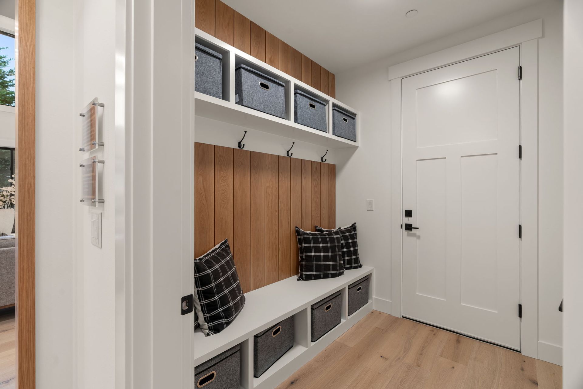 Modern walk-in shower with glass doors, beige tile, black vanity, and white toilet in a bathroom