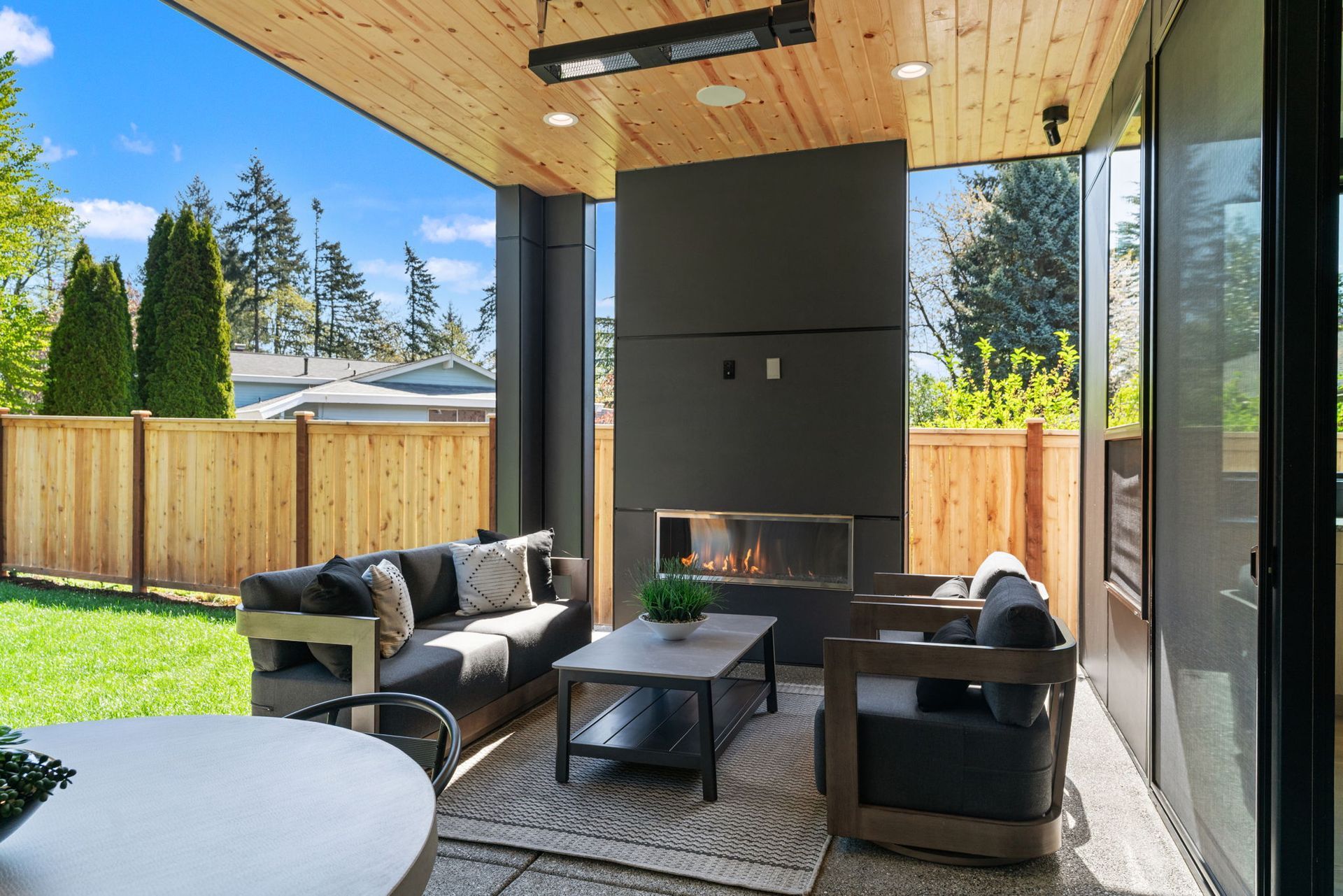 Modern covered patio with fireplace, wicker seating, and sliding glass doors
