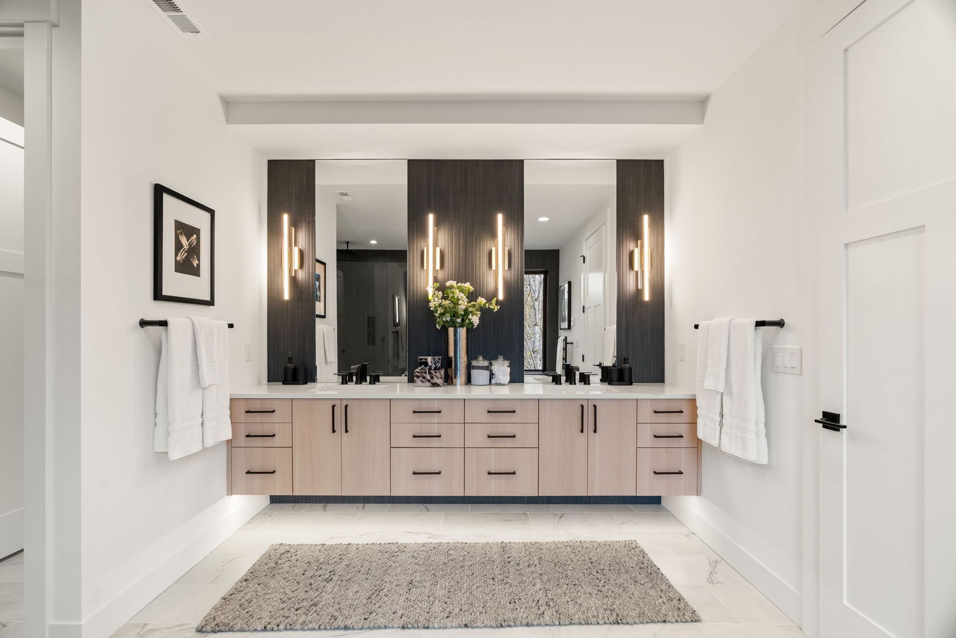 Modern bathroom with double vanity, light wood cabinets, and large mirrors.