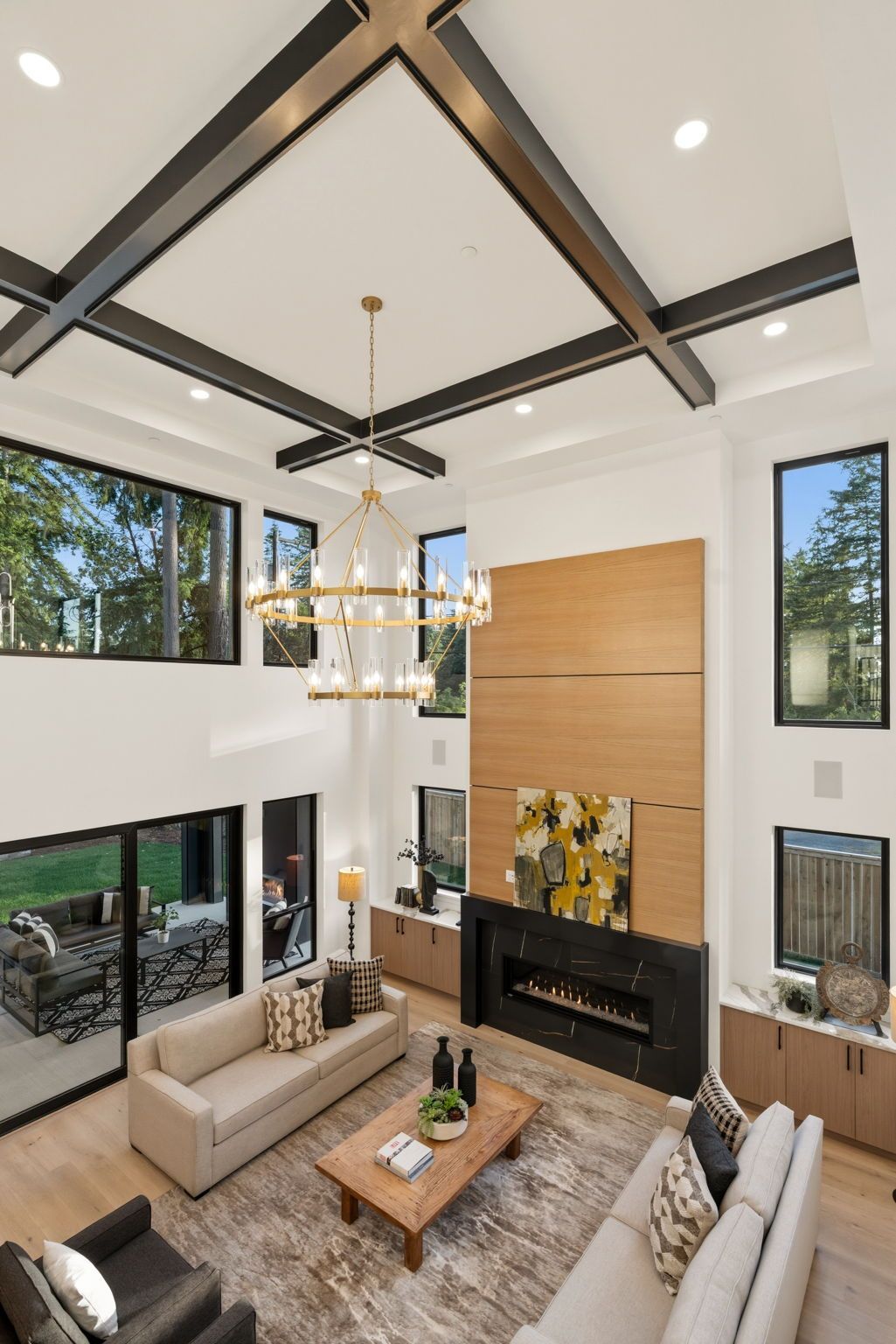 Bright foyer with wood floors, staircase, black railing, and modern pendant lights.