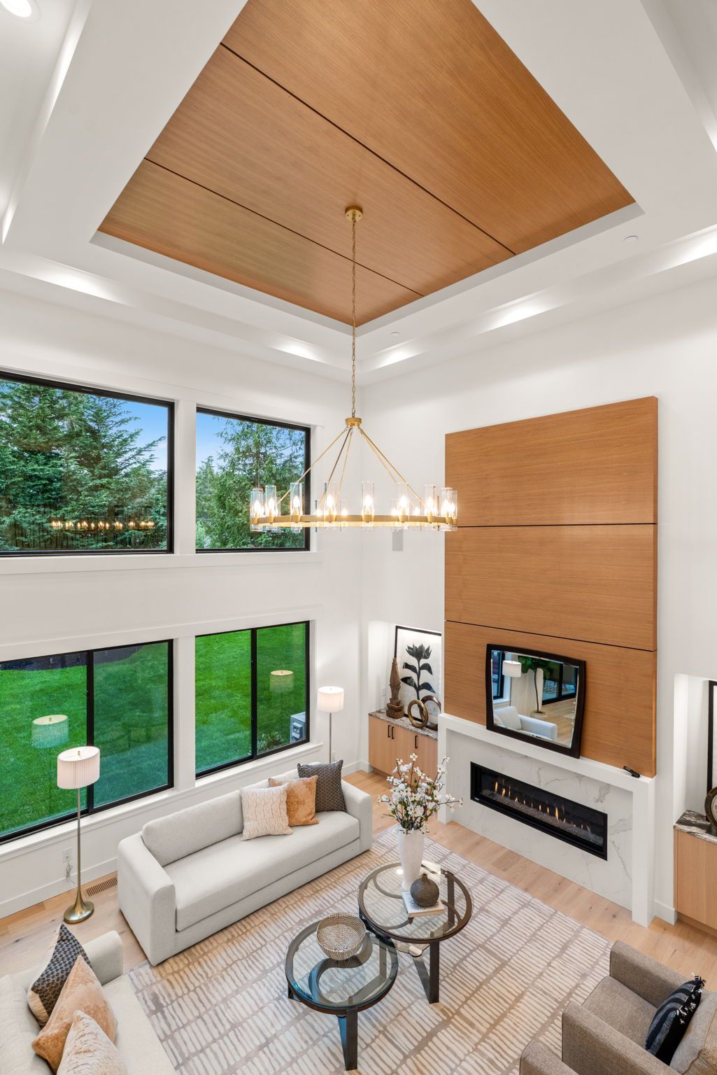 Modern living room with vaulted wood ceiling, large windows, white sofa, fireplace, and glass coffee table
