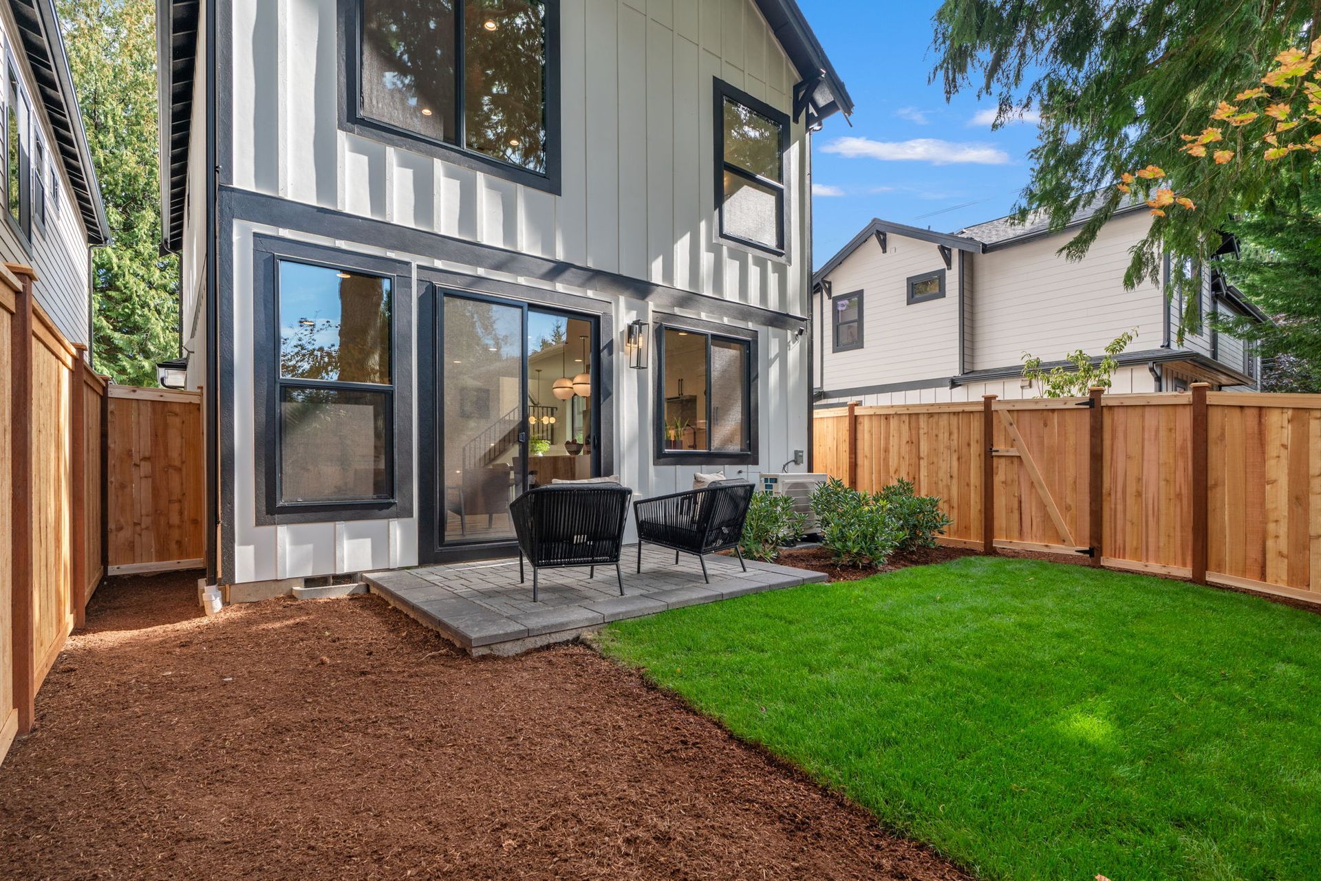 Exterior renderings of modern two-story townhomes with white siding, dark trim, and black garage doors.