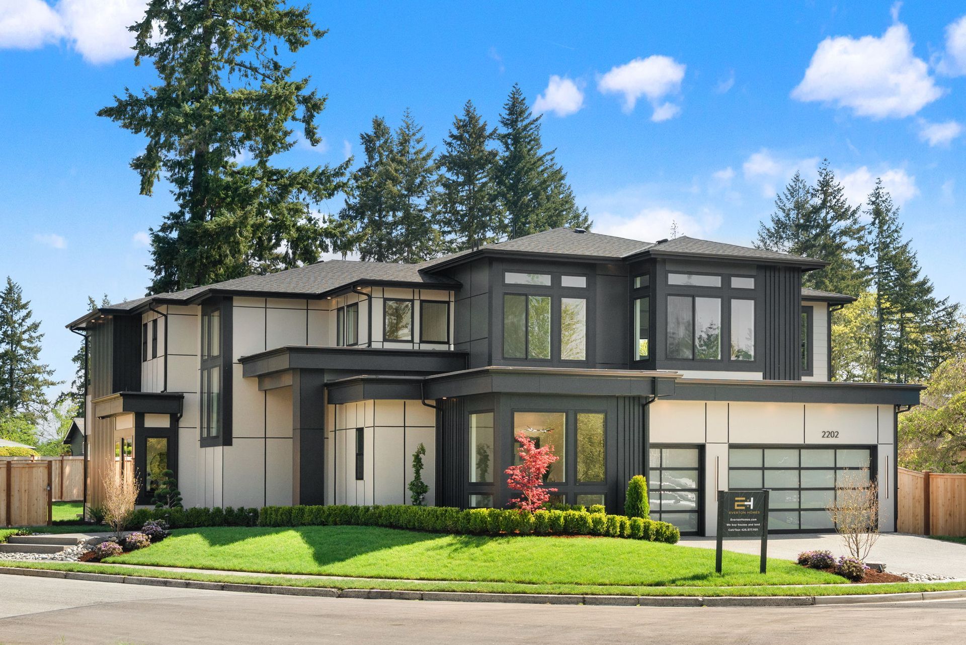 Modern two-story suburban house with gray exterior, black trim, and a manicured lawn under a blue sky
