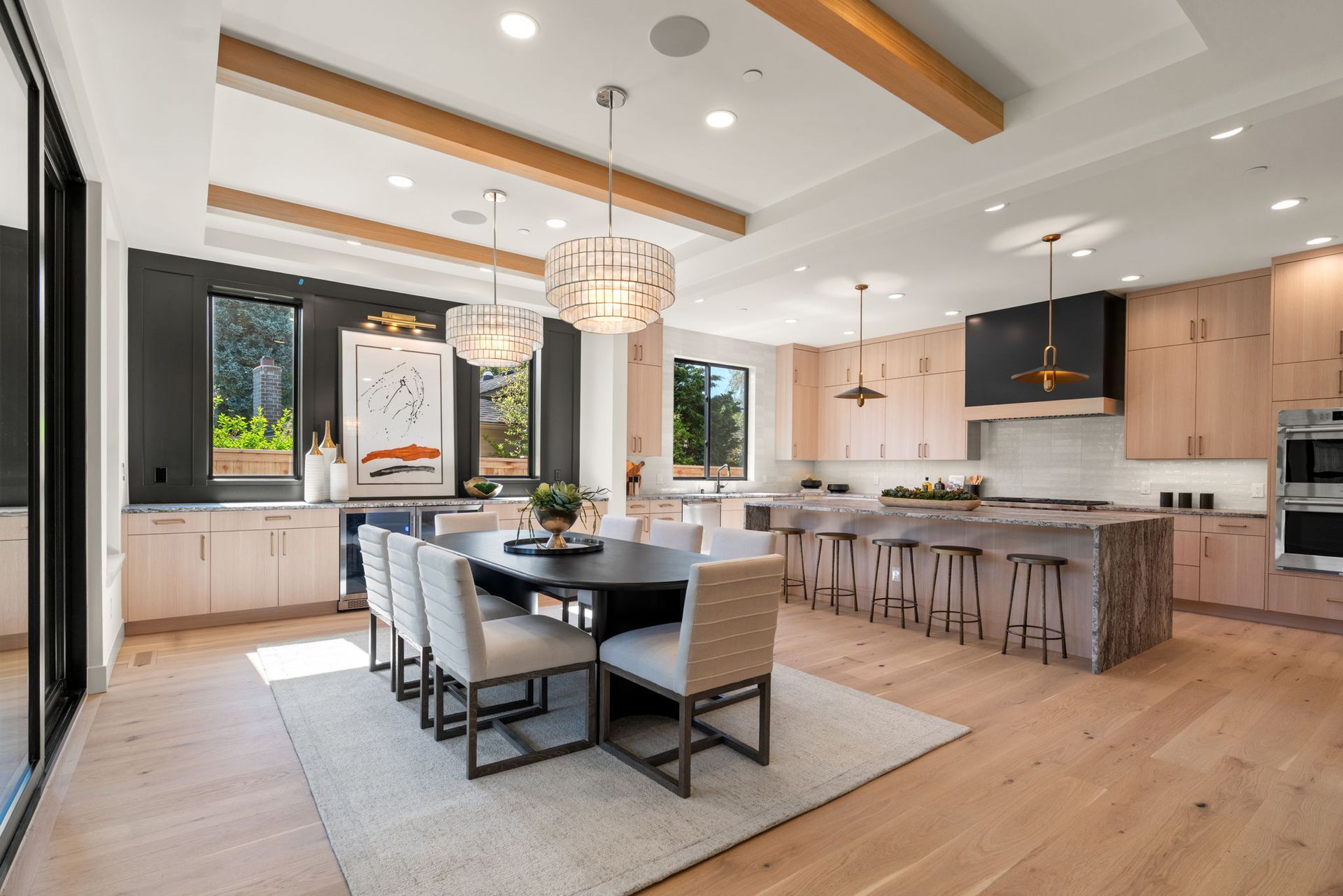 Bright modern kitchen and dining area with island, wood accents, and large windows
