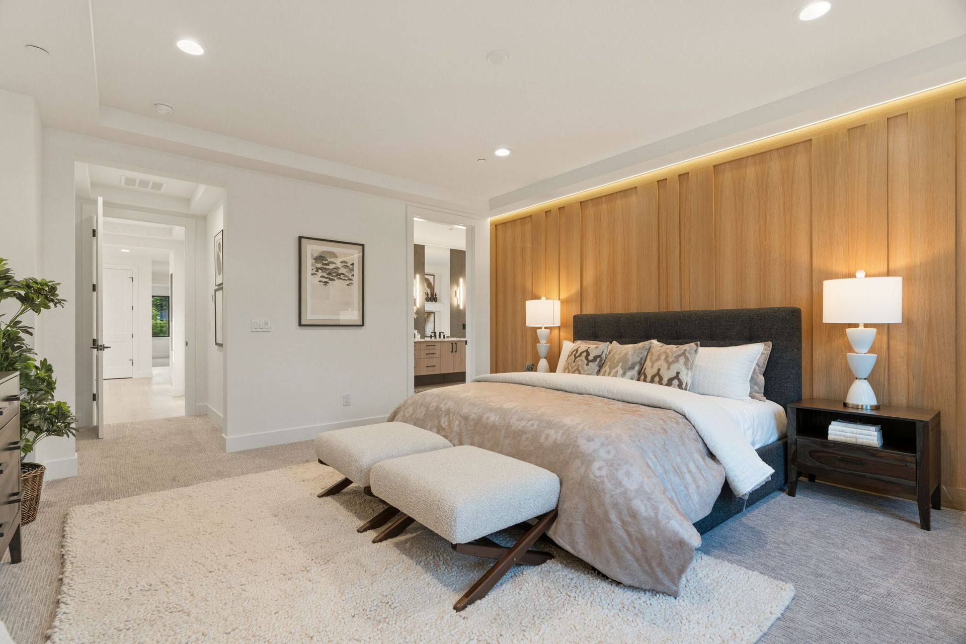 Bright modern bedroom with a tufted bed, bench, wood accent wall, and soft neutral decor
