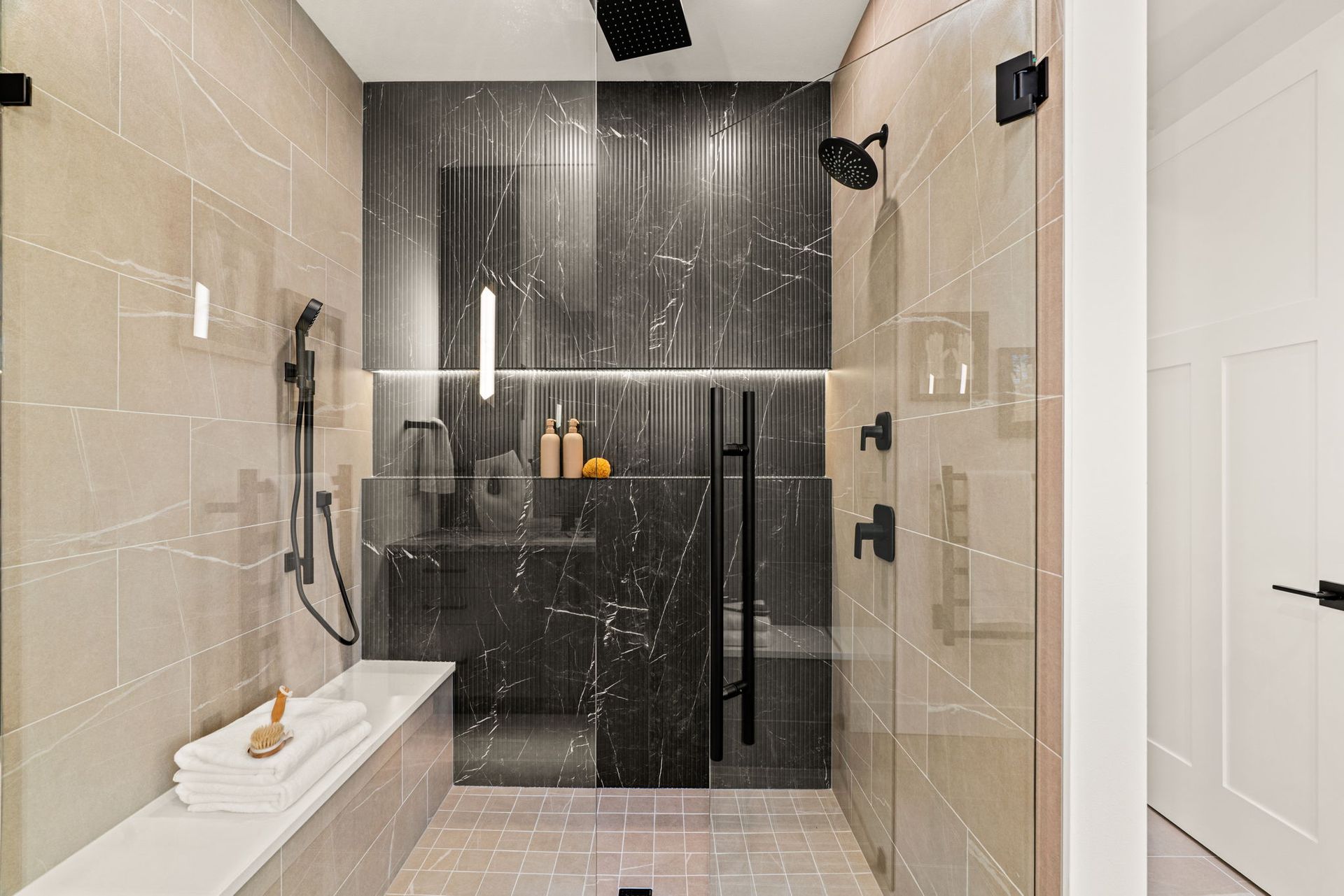 Modern bathroom with freestanding tub, double vanity, dark tile walls, and a snowy view through large windows