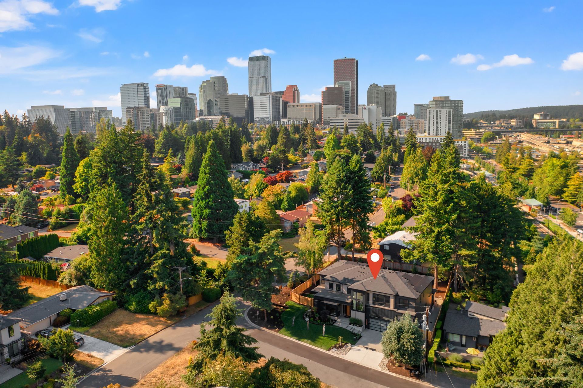 City skyline behind a leafy residential neighborhood with streets and homes in the foreground