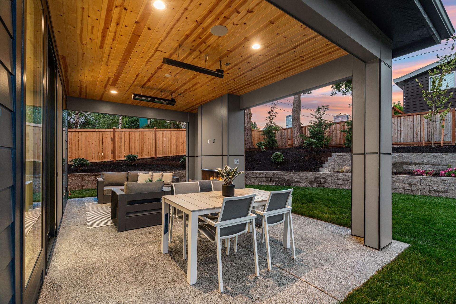 Covered patio with dining table, lounge seating, and grassy backyard under a wood ceiling
