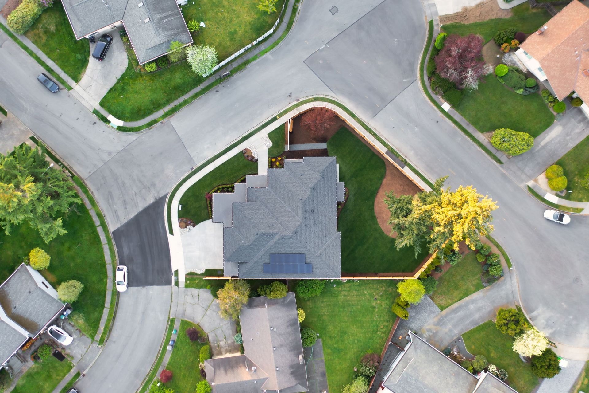 Aerial view of a suburban neighborhood with houses, curved streets, and green lawns.