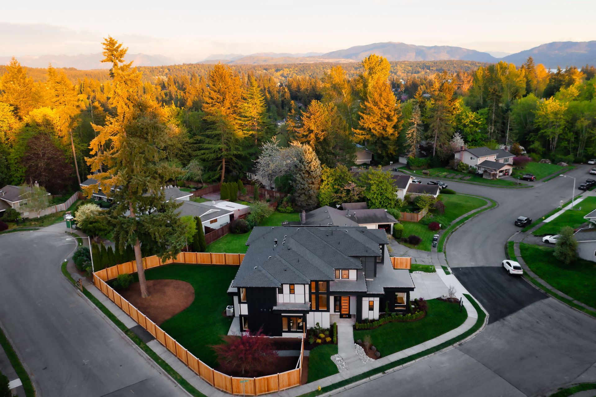 Aerial view of a suburban house with autumn trees and curving streets at sunset