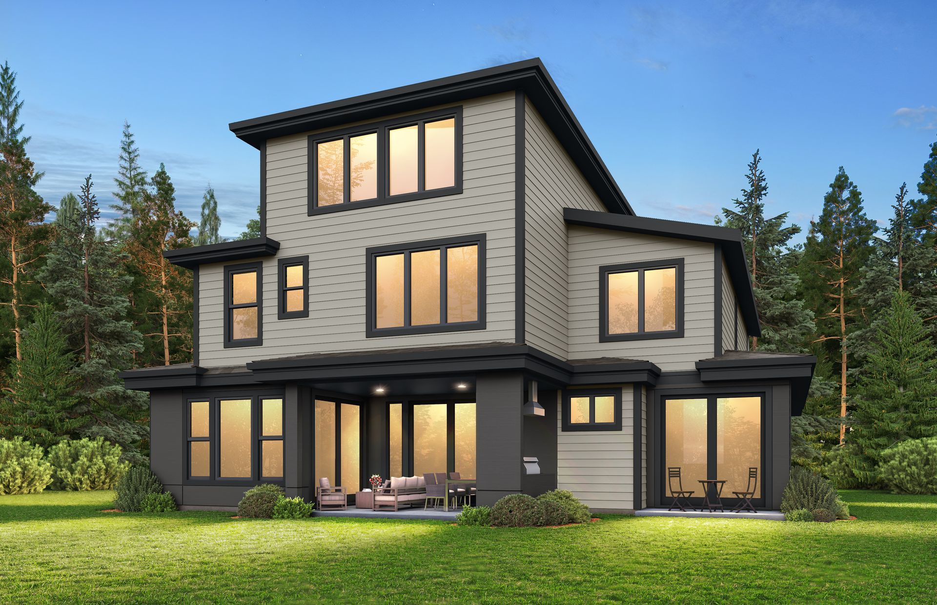A three-story modern house with light siding and dark trim, set in a grassy clearing surrounded by a pine forest.