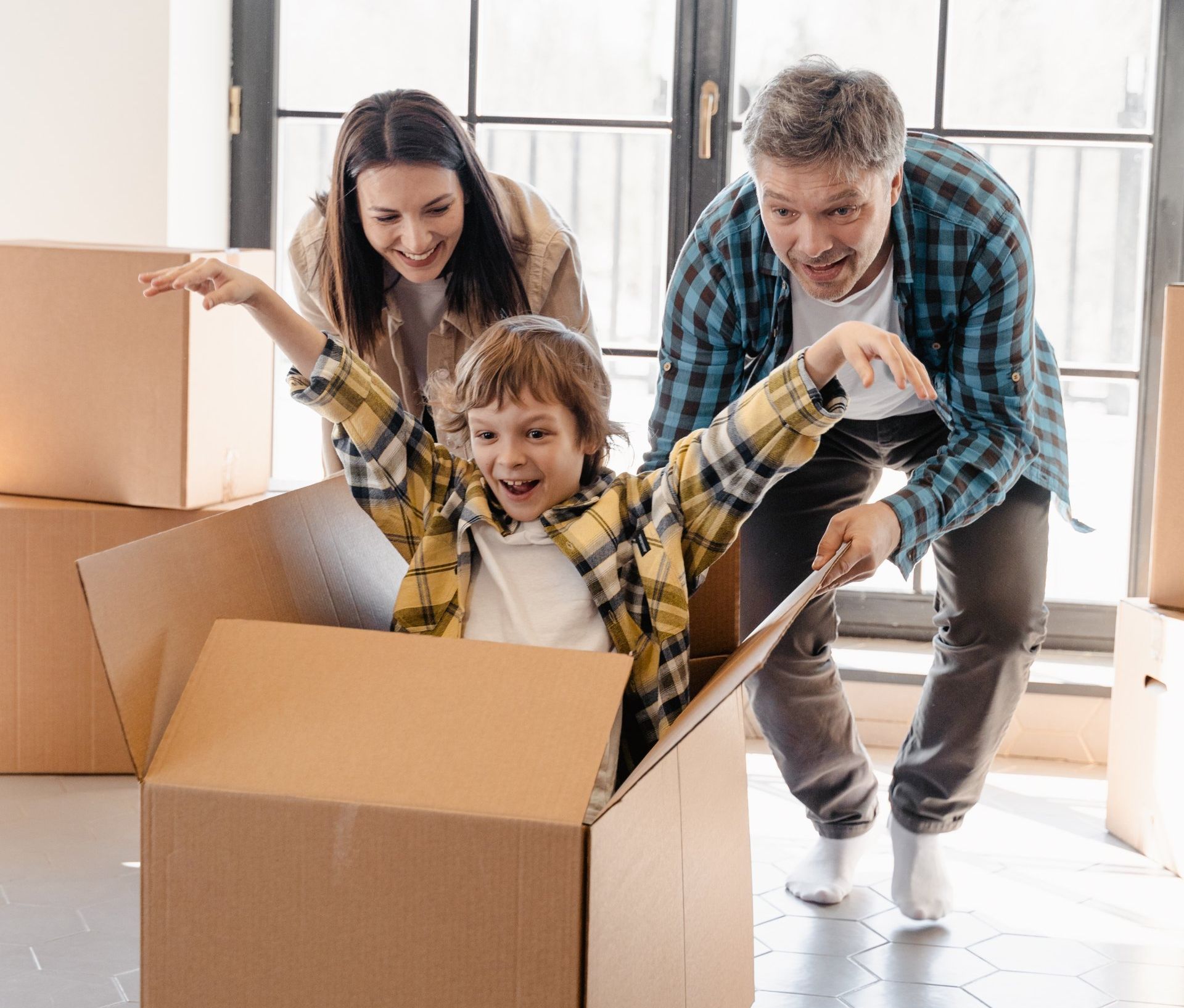 A family is playing in a cardboard box in a new home.